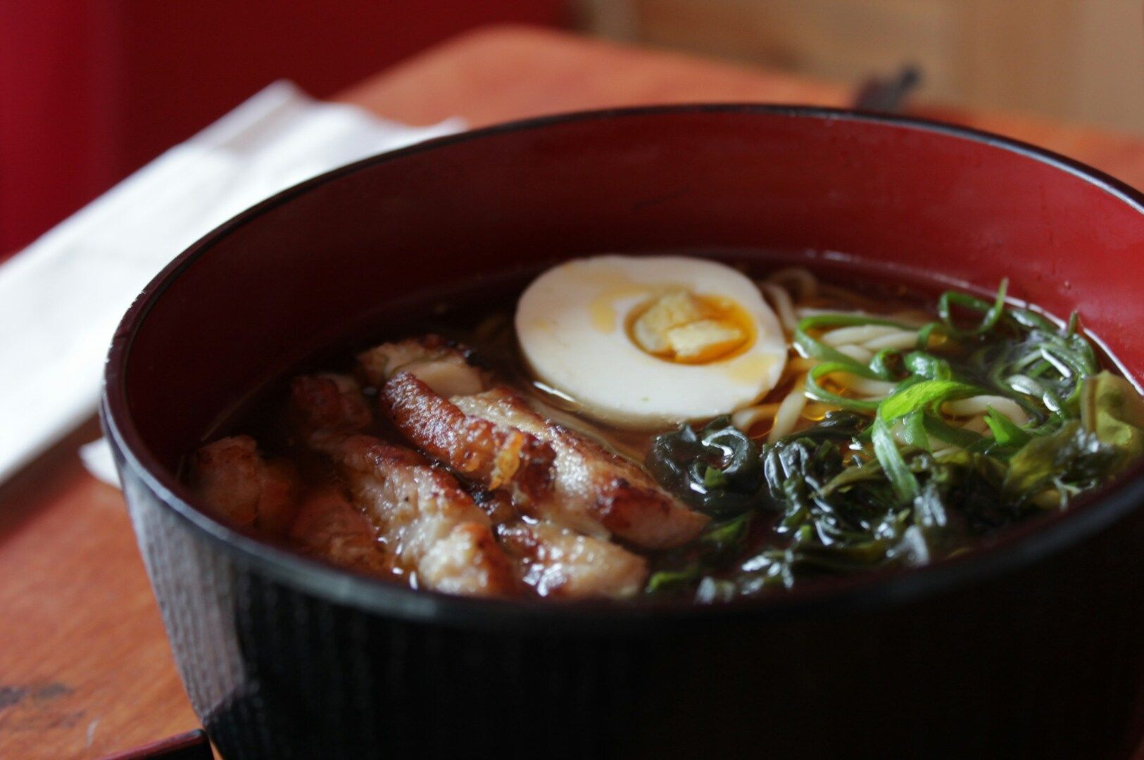 Grilled chicken ramen served in a bowl, featuring a soft-boiled egg and tender meat pieces.