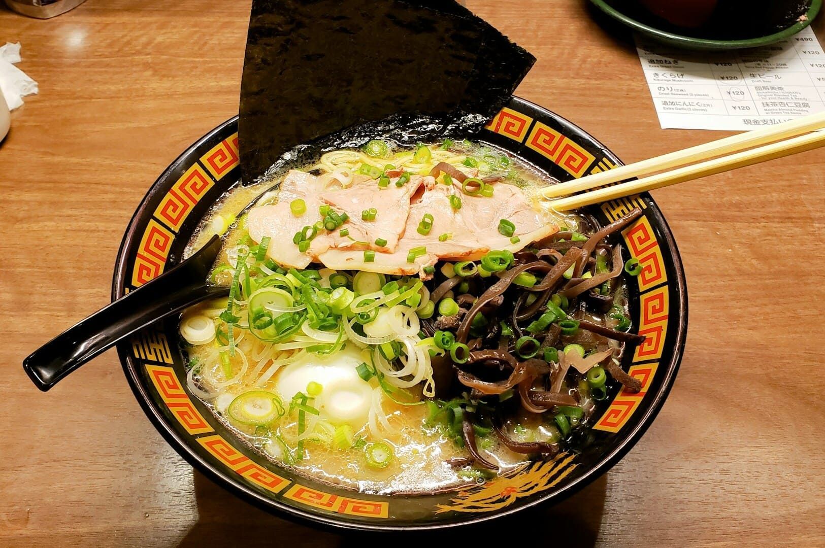 A bowl of Ichiran Ramen, featuring Hakata-style noodles, accompanied by chopsticks and a spoon.