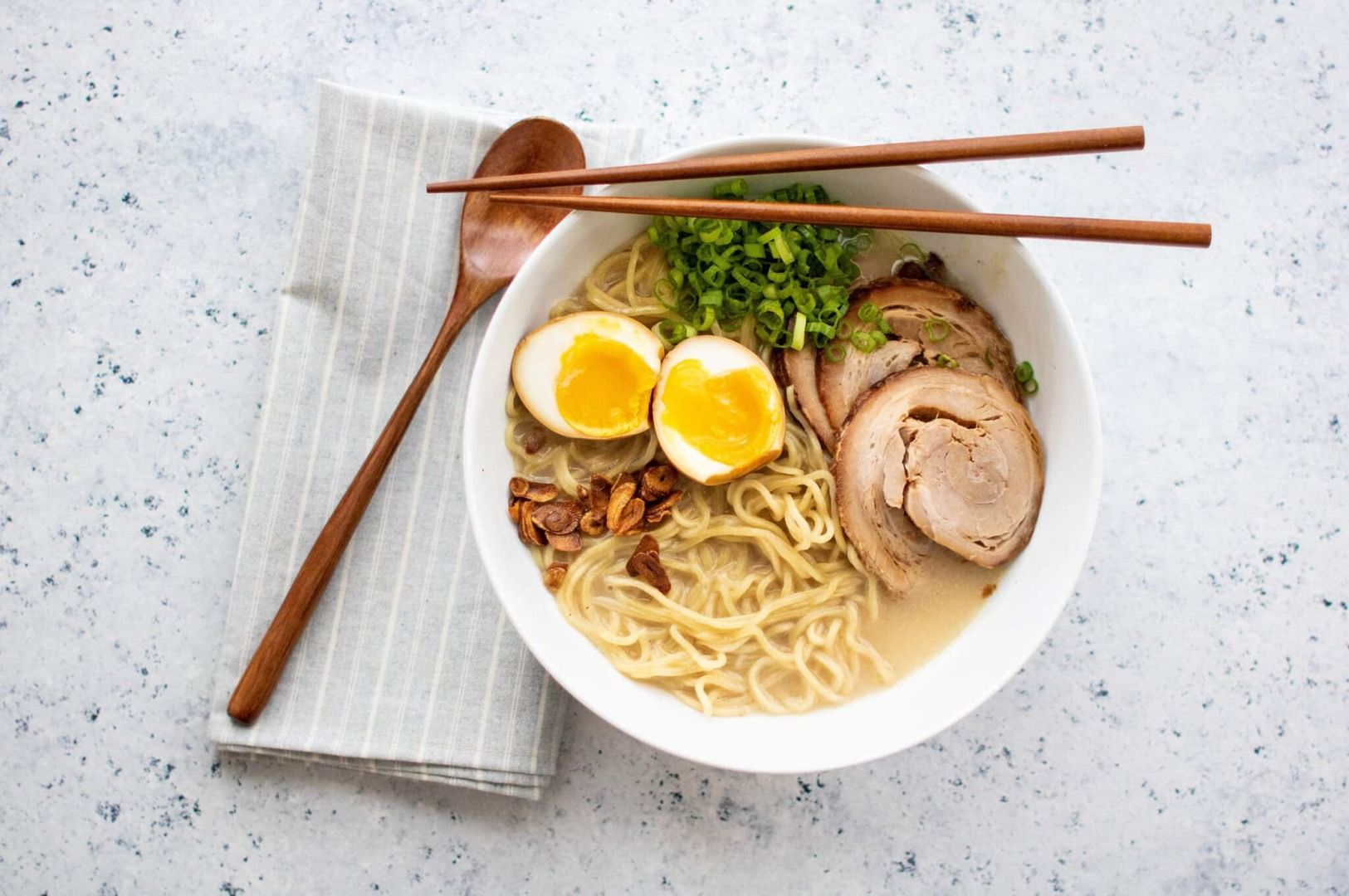 A bowl of Tonkotsu Ramen featuring tender pork slices and a soft-boiled egg, garnished with green onions.
