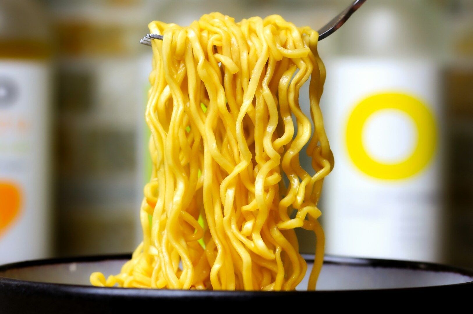 A spoonful of noodles from a bowl of Korean dry ramen, highlighting the dish's appetizing appearance and texture.