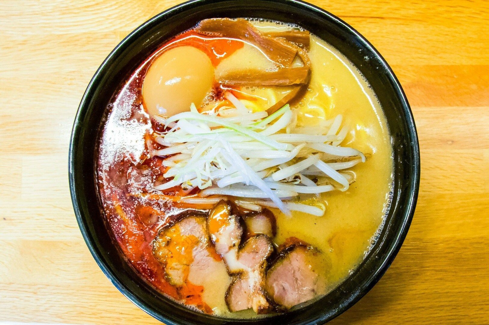 A bowl of miso ramen topped with tender meat and fresh vegetables, served in a traditional Japanese.