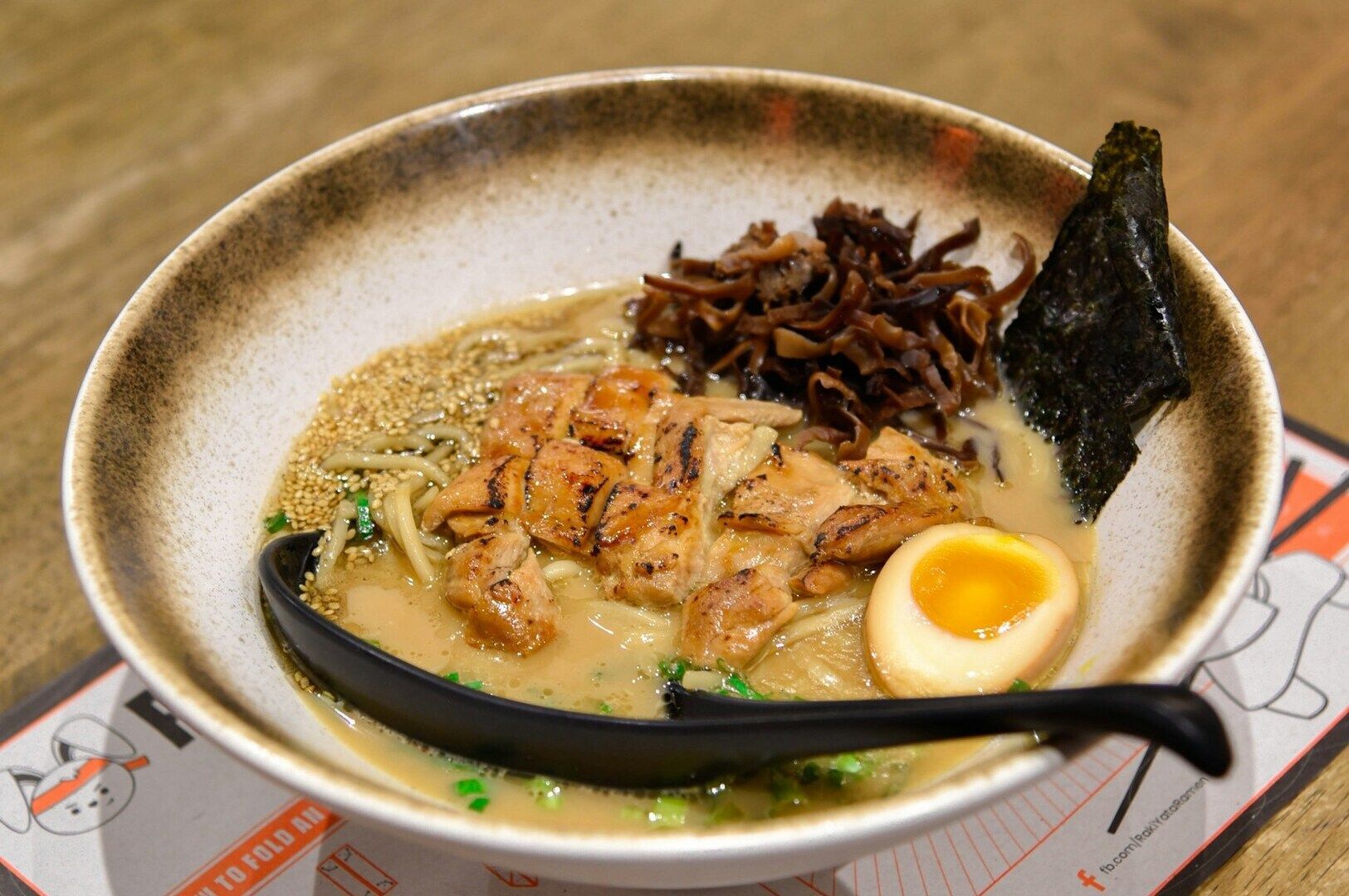 A steaming bowl of ramen featuring savory broth, a soft-boiled egg, and tender meat slices.