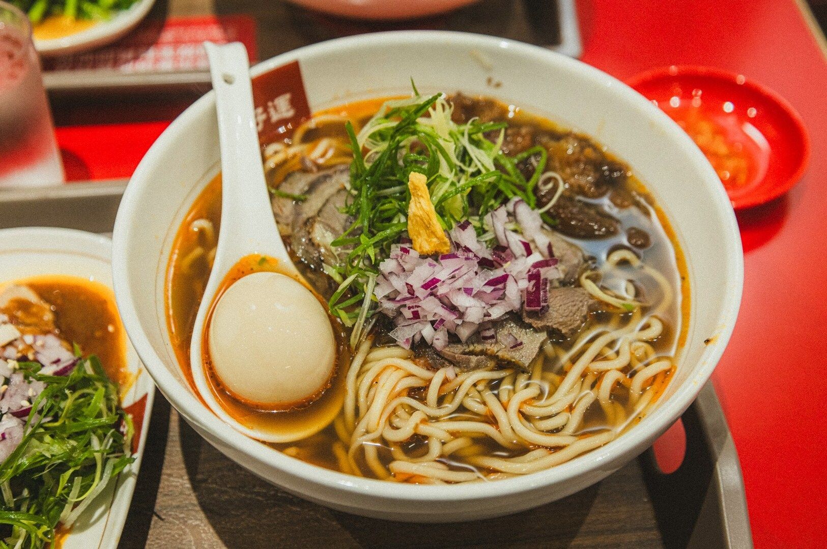 A steaming bowl of ramen with savory broth, assorted meat, and vibrant vegetables, ready to be enjoyed.
