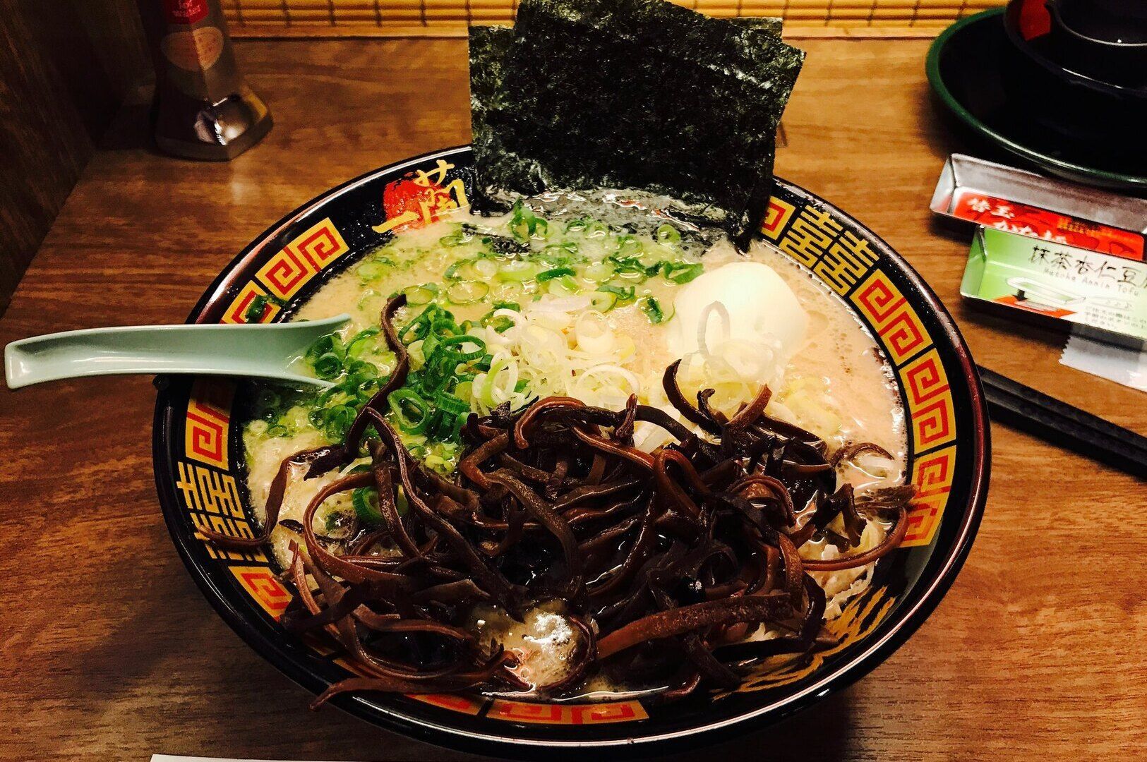Tonkotsu Black Ramen in a bowl, showcasing noodles mixed with fresh vegetables.