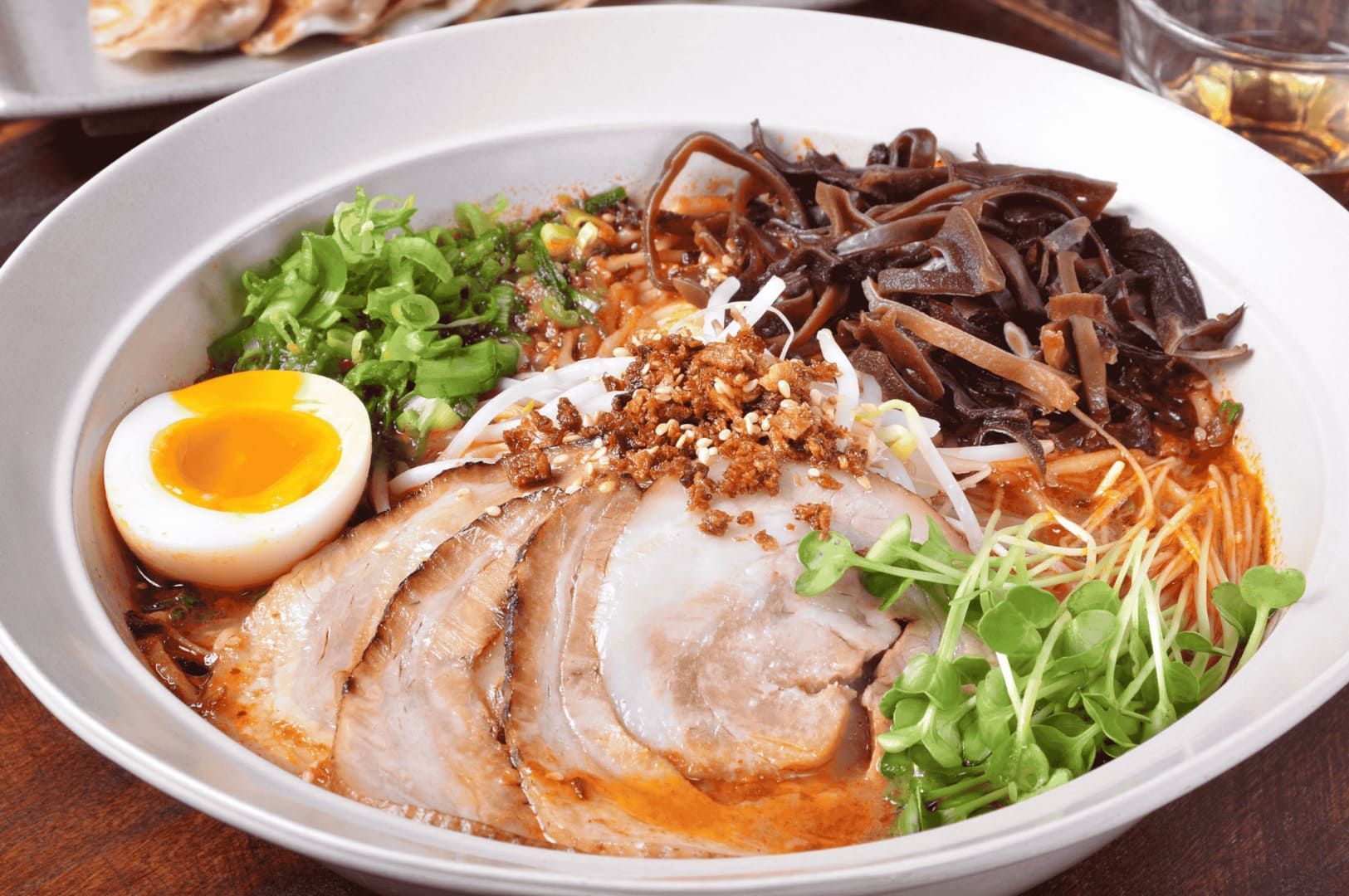 Tonkotsu Black Ramen served in a bowl, featuring meat, eggs, and assorted vegetables.