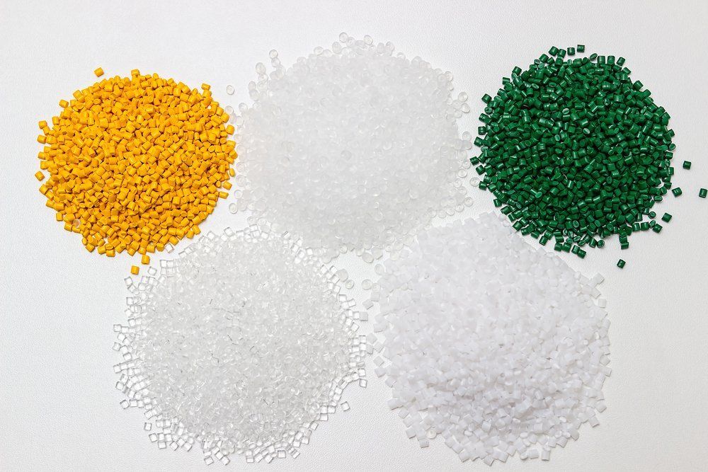 Three piles of different colored plastic granules on a white surface