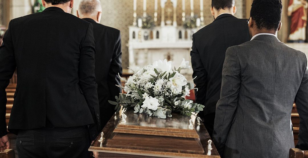 A group of men in suits are carrying a coffin in a church.