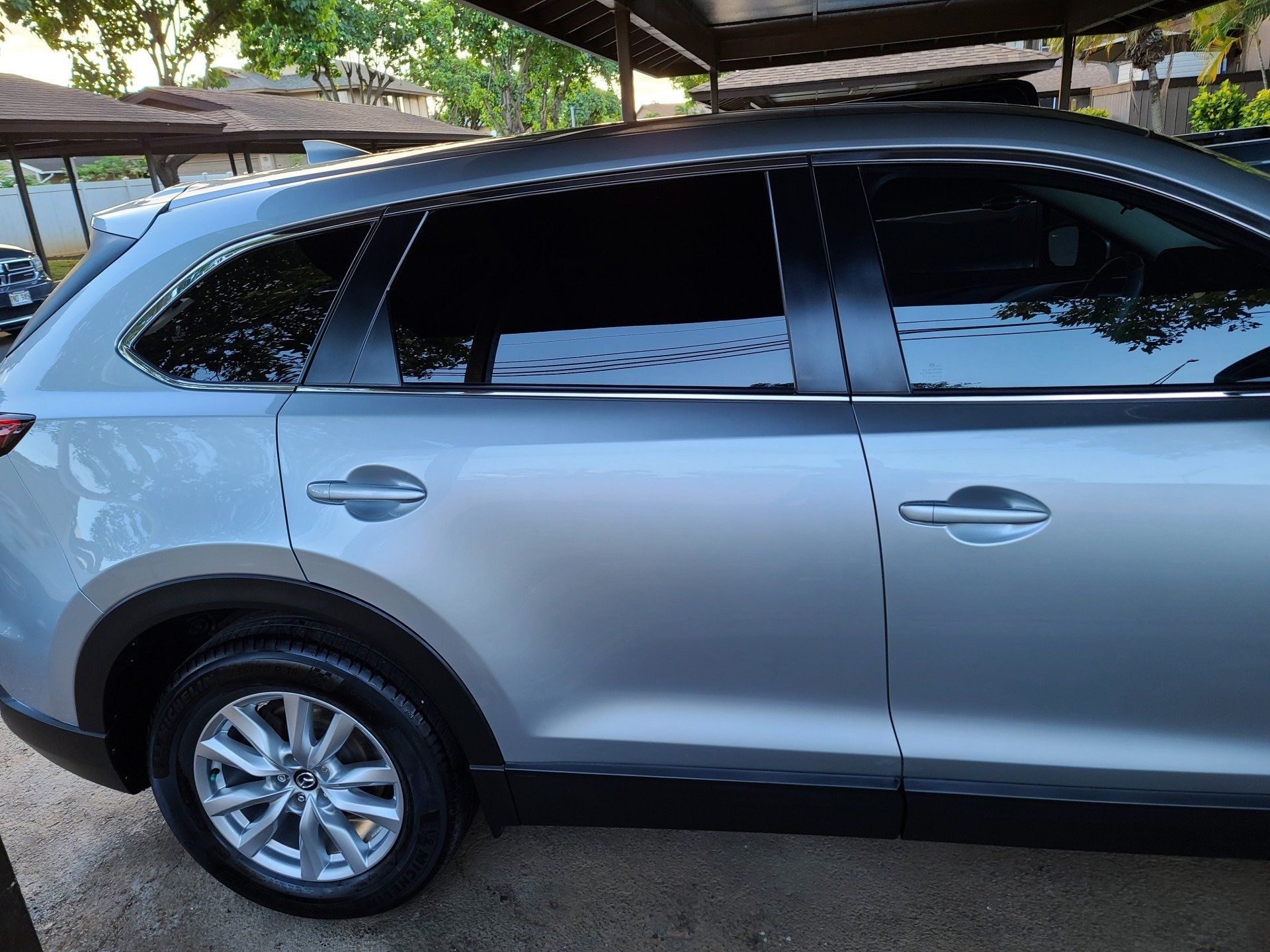 Silver SUV with tinted windows parked under a carport.