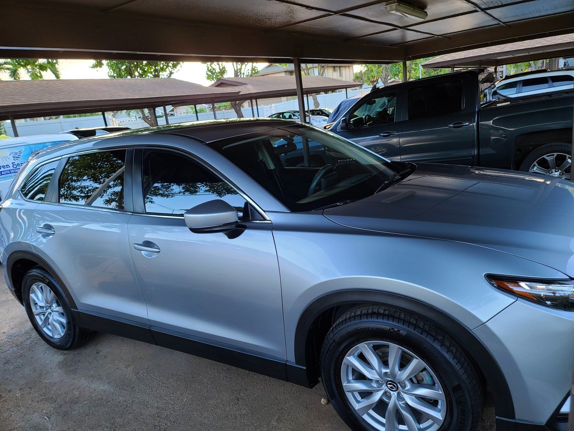 Silver Mazda CX-9 SUV parked under a covered area, with tinted windows and black trim.