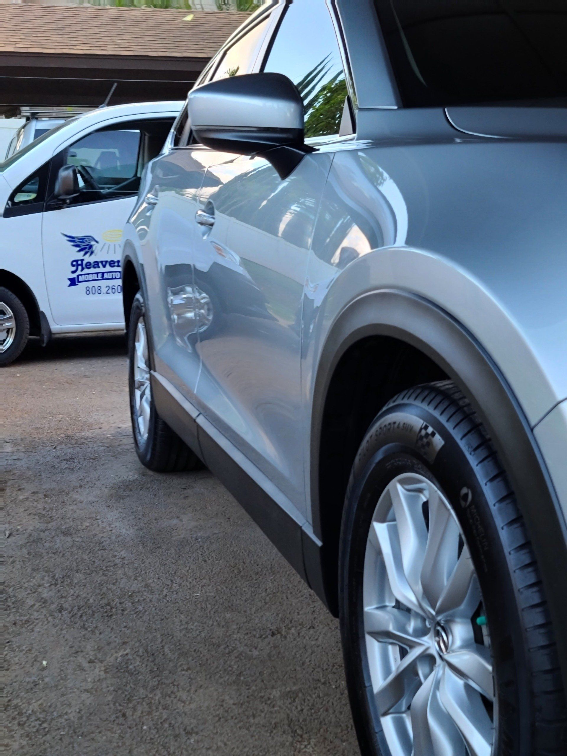 Silver SUV with black trim and a white van in the background, parked outdoors.