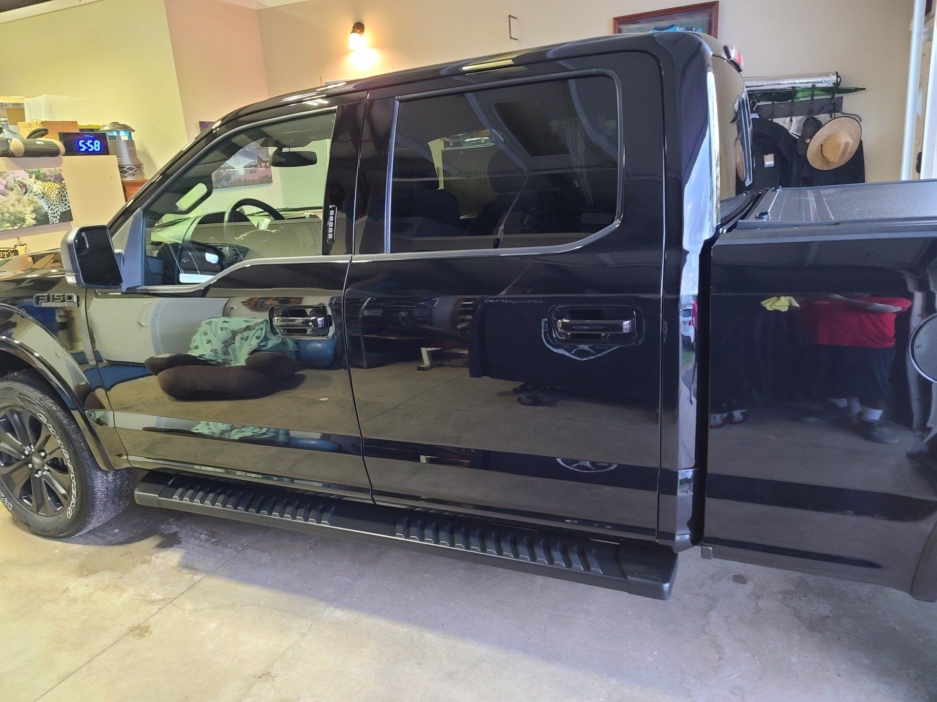 Black Ford F-150 truck with running boards parked inside a garage.
