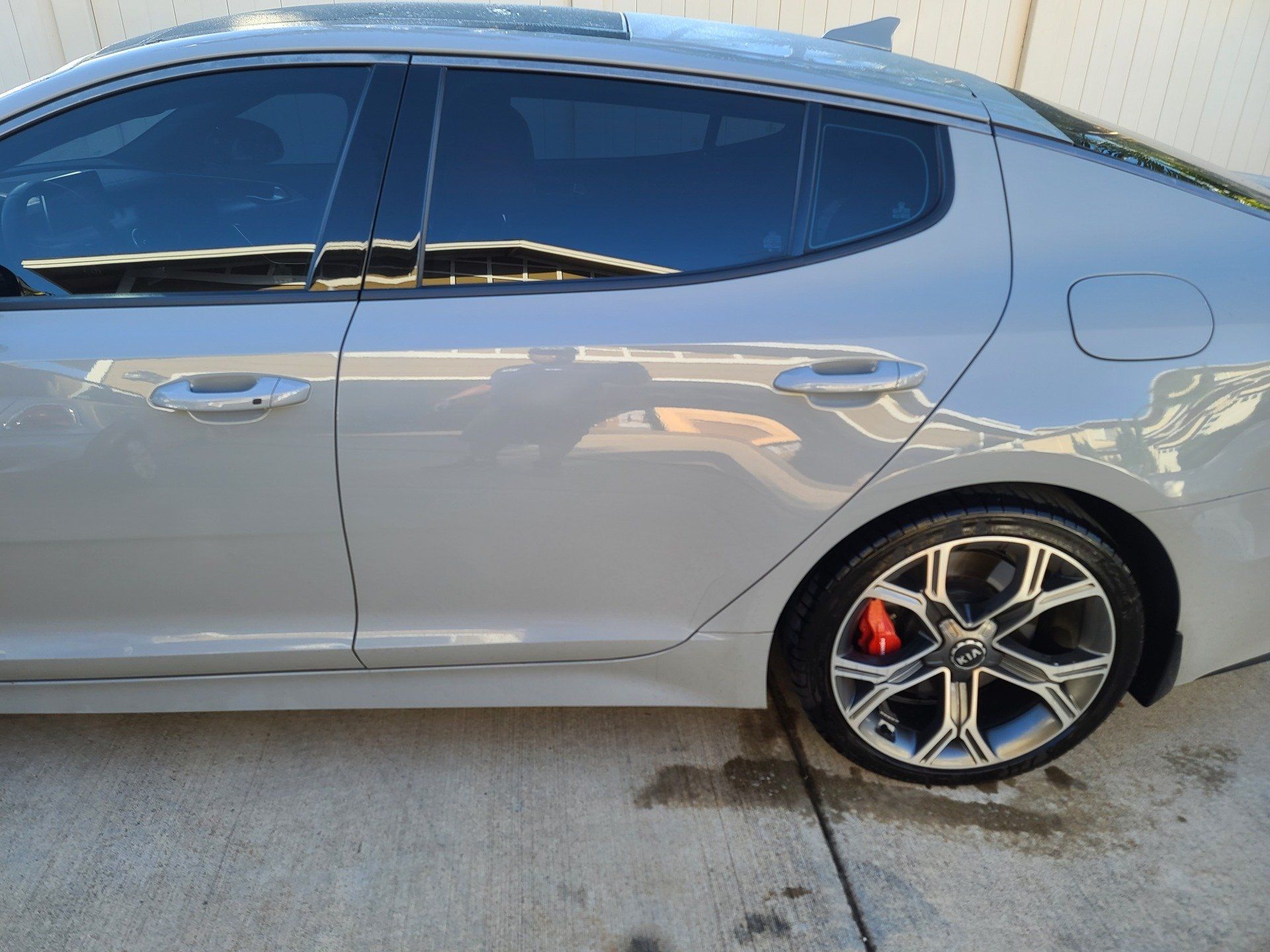 Gray Kia Stinger with tinted windows and red brake calipers, parked outside.