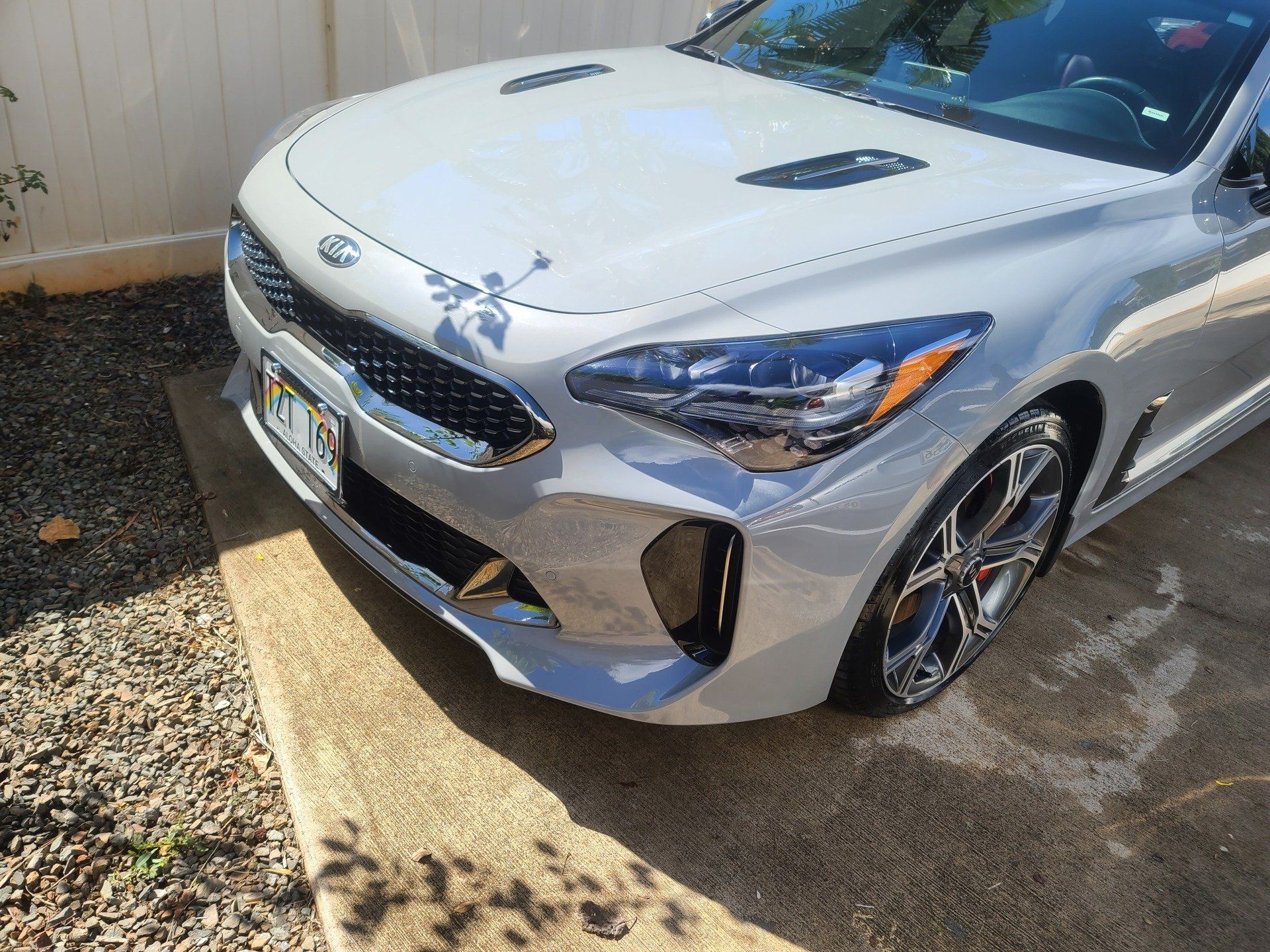 Silver Kia Stinger sports car parked on a concrete driveway.