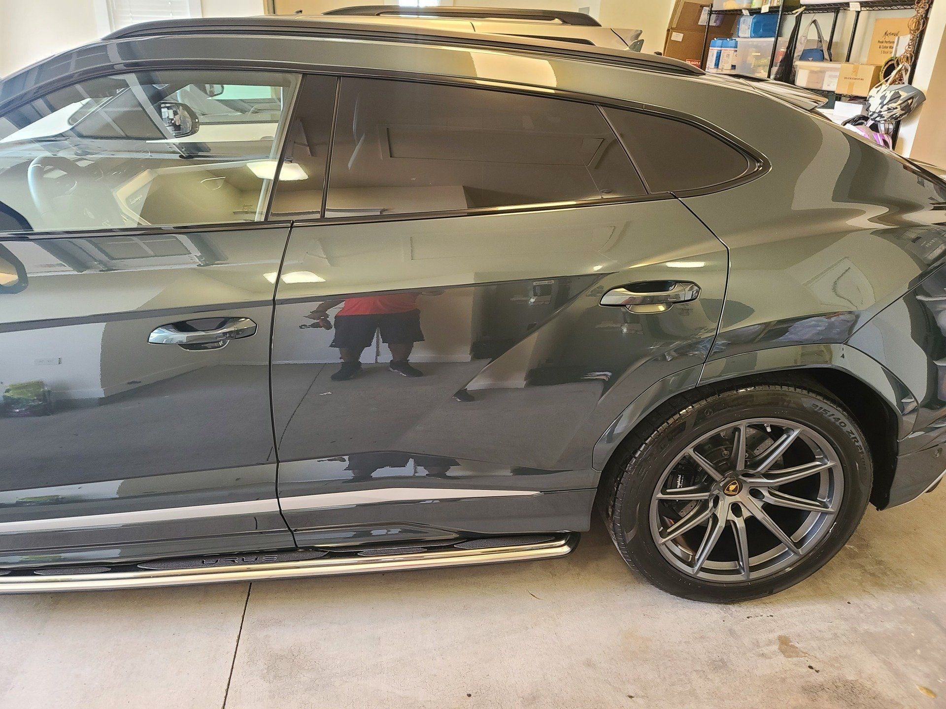 Gray Lamborghini SUV parked in a garage with tinted windows and silver side steps.