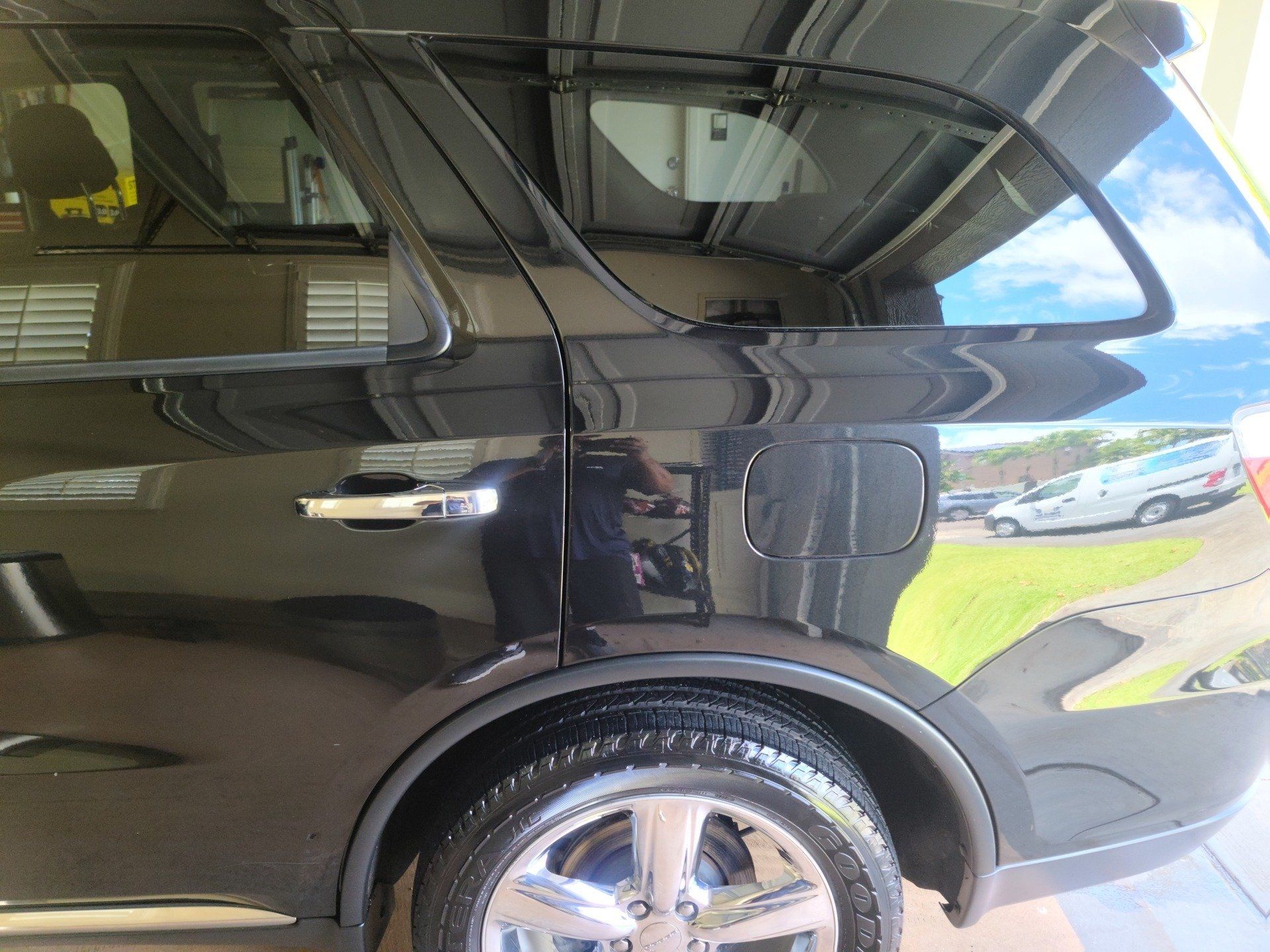 Black SUV parked outdoors, shiny paint, reflective surfaces, chrome wheel.