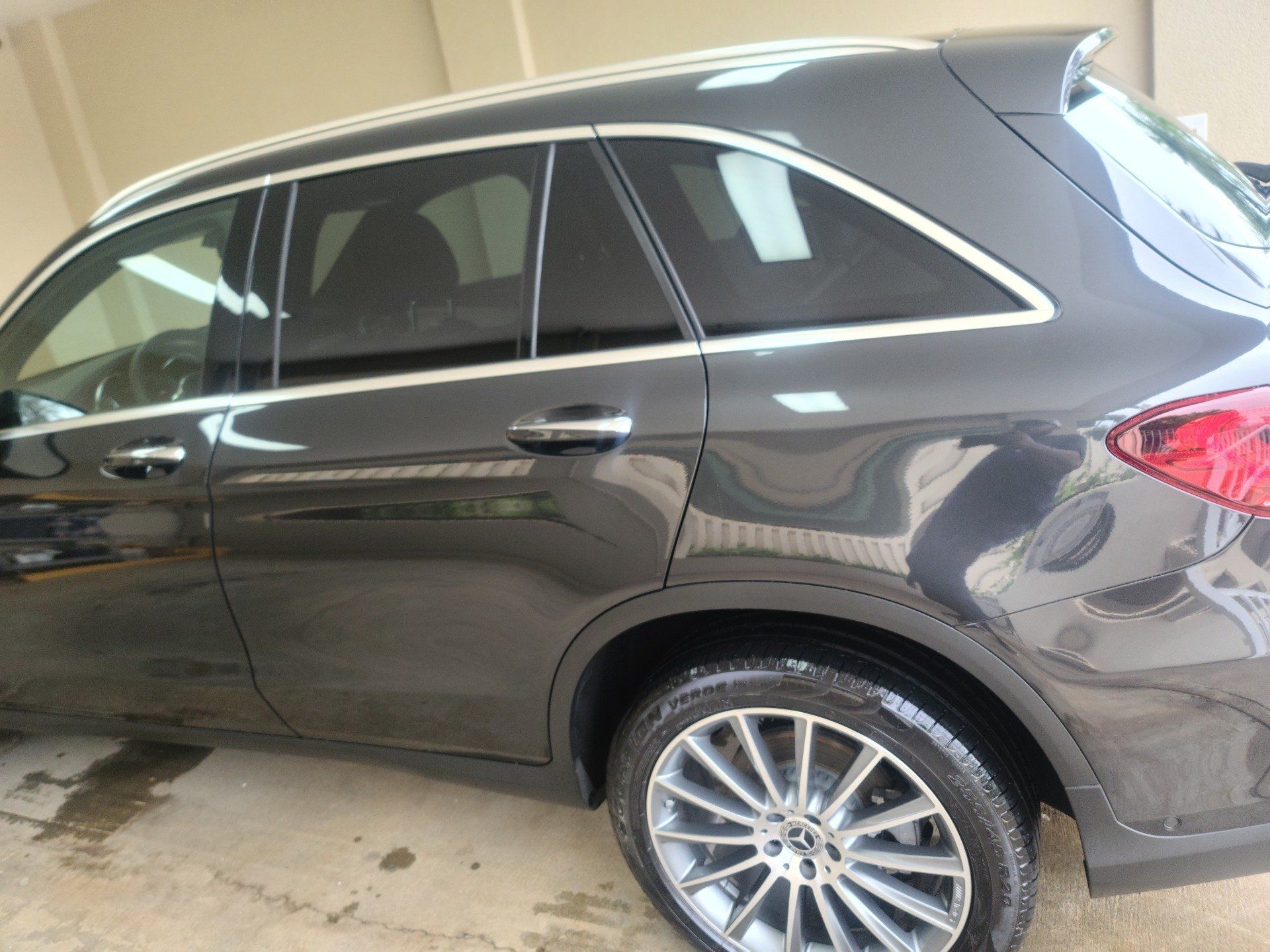 Gray Mercedes-Benz SUV with tinted windows parked indoors; showing side view of the car with shiny wheels.