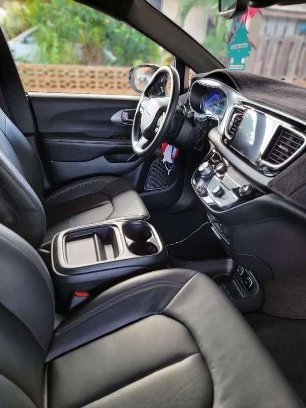Black leather interior of a Chrysler Pacifica minivan, showing the driver's seat, dashboard, and center console.