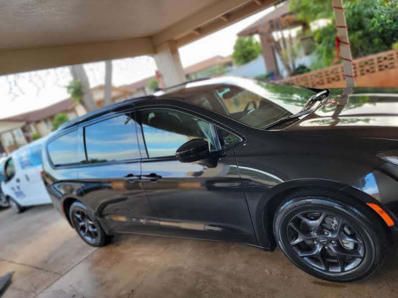 Black Chrysler Pacifica minivan parked under a carport.