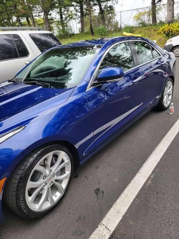 Blue Cadillac sedan parked in a lot, sunny day.