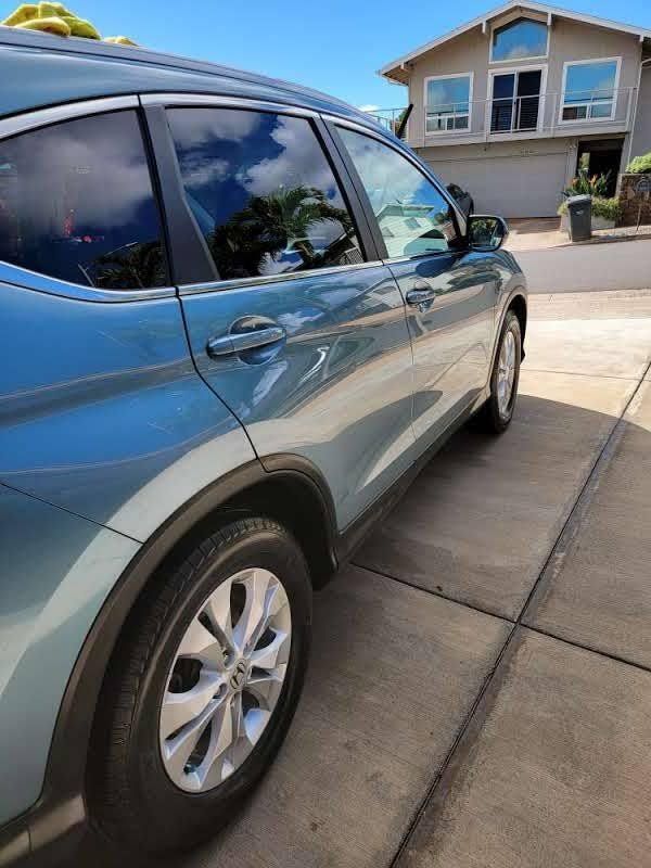 Blue SUV parked in driveway, house in background.