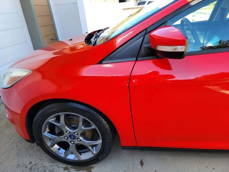 Red Ford Focus car parked outside with a gray wheel.