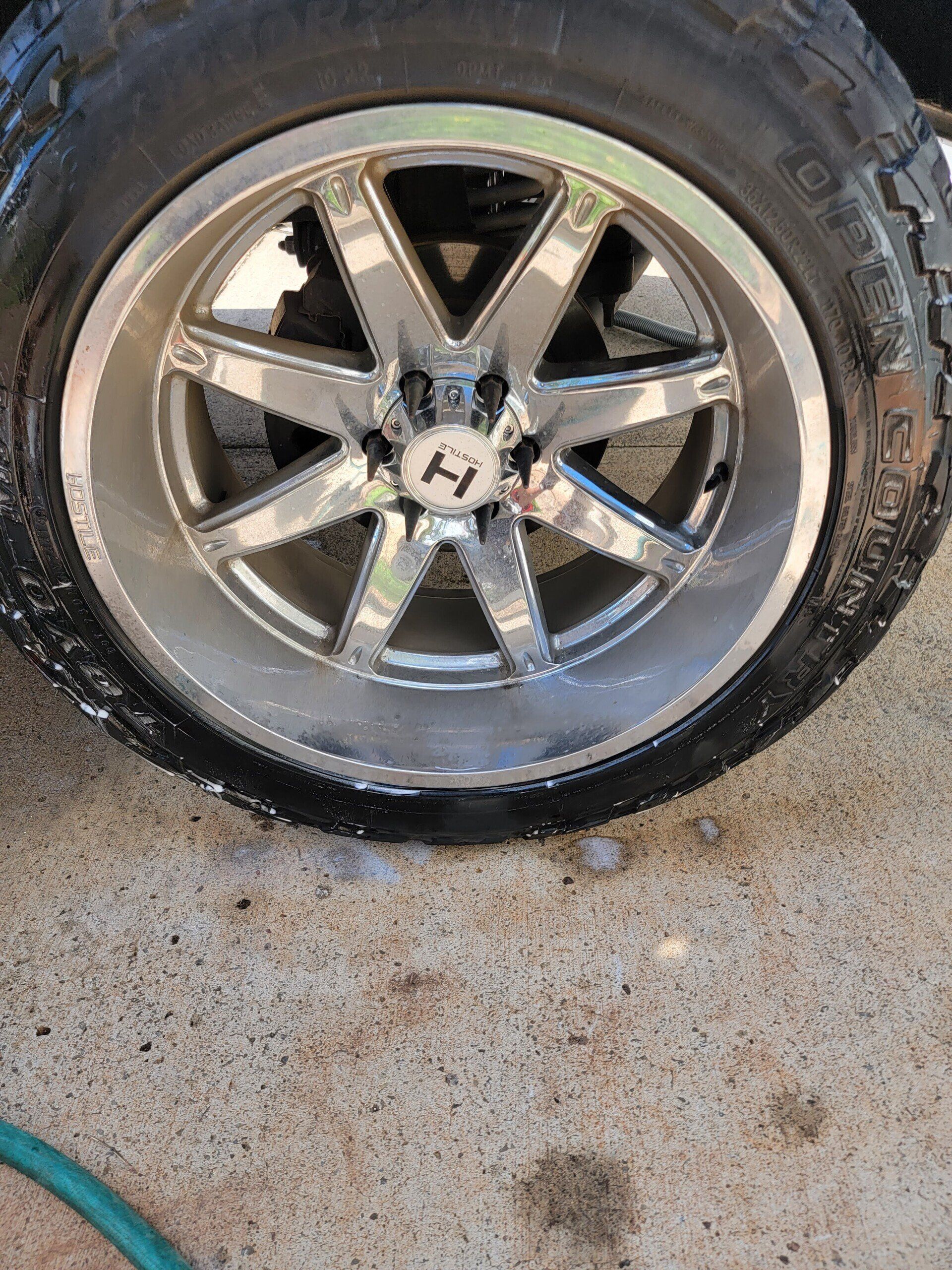 Shiny chrome car wheel with a black tire on a concrete surface.