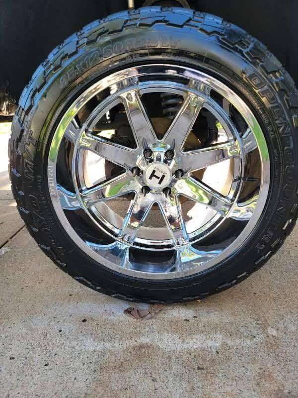 Shiny chrome wheel with black tire on a concrete surface.