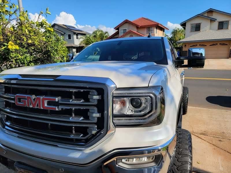 White GMC Sierra truck parked on a street in a residential neighborhood.