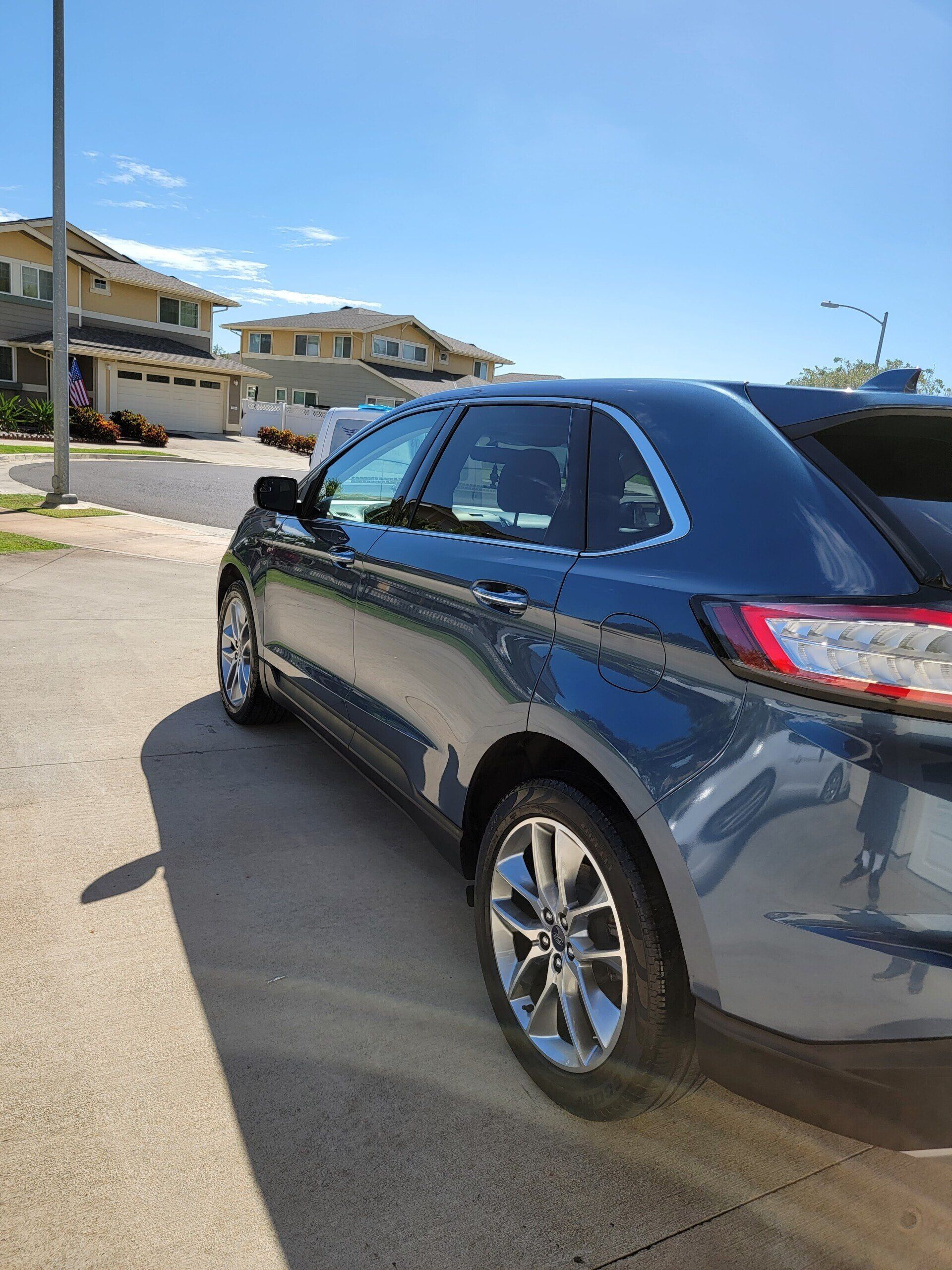 Blue Ford Edge parked on a sunny residential street.