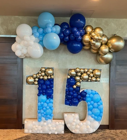 The number 15 is decorated with blue and gold balloons