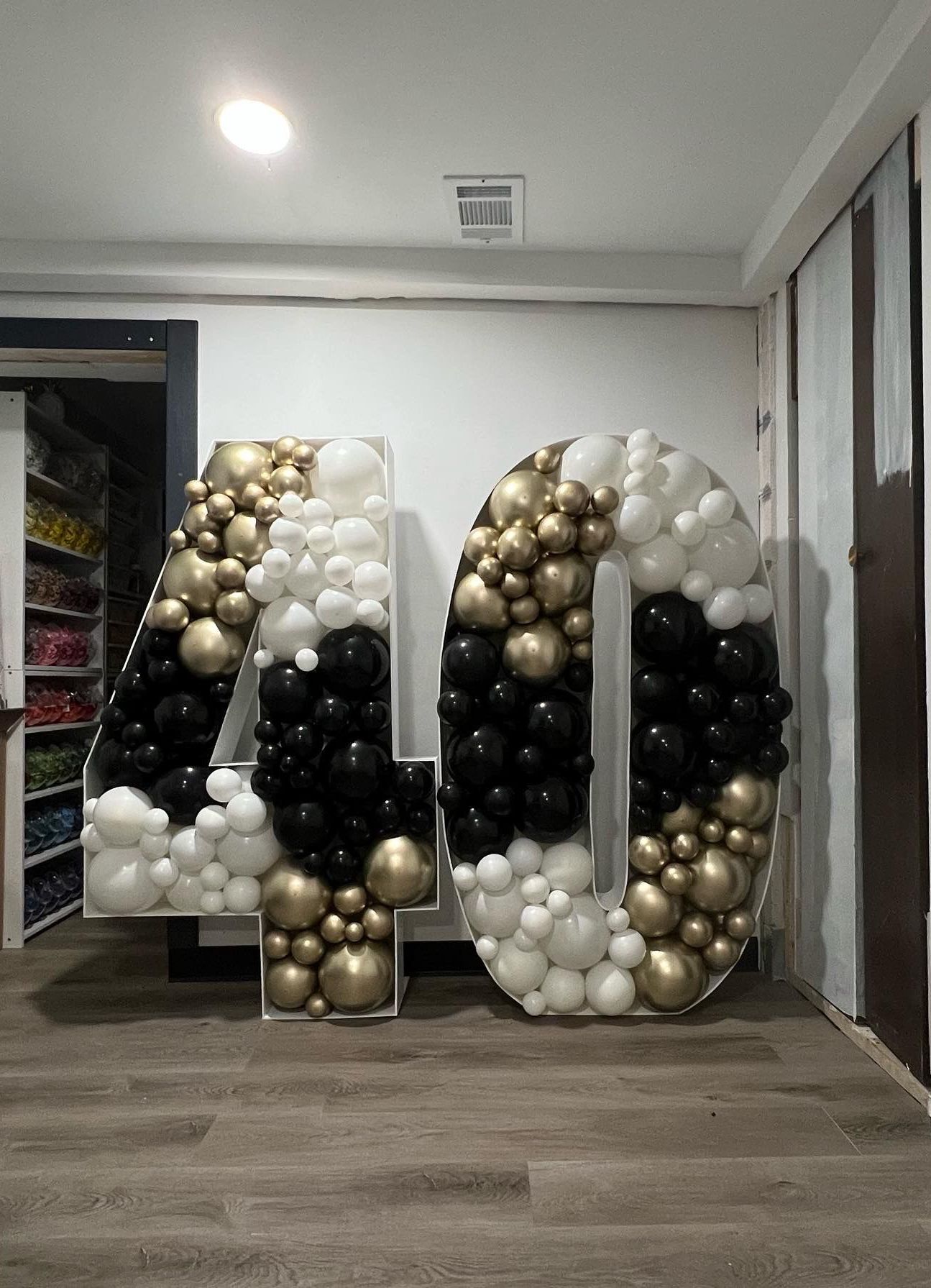 The number 40 is made of black , white and gold balloons.