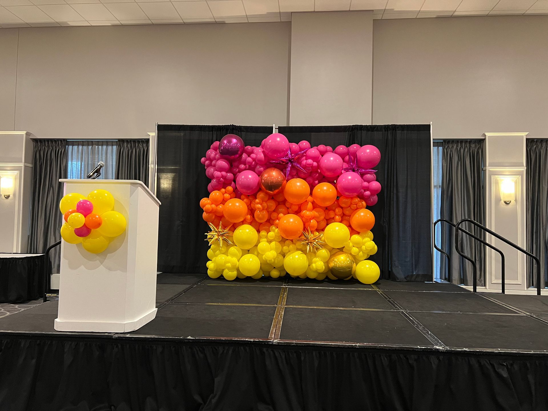 A stage decorated with balloons and a podium in a room.