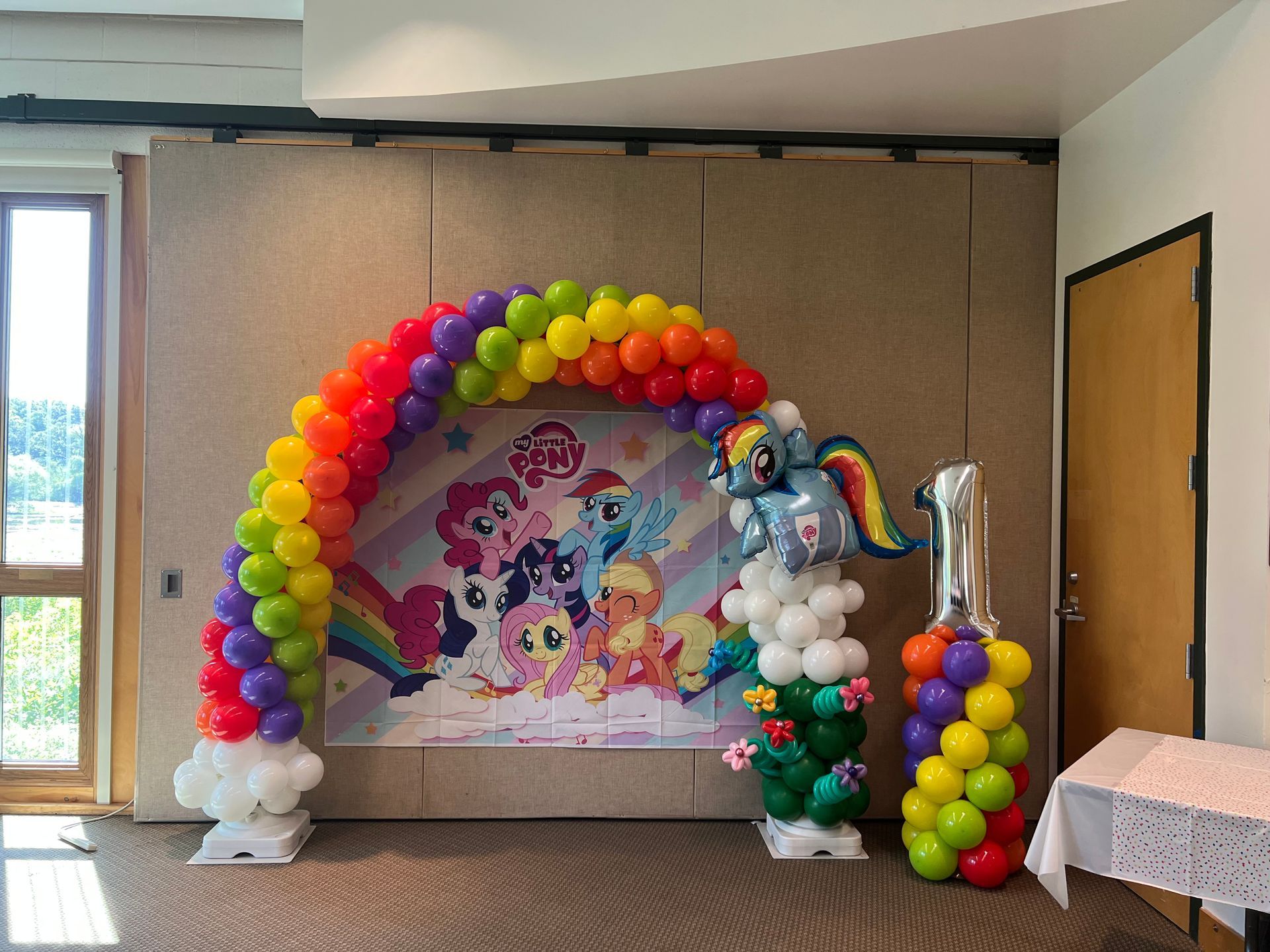 A room decorated with balloons and a picture of my little pony.
