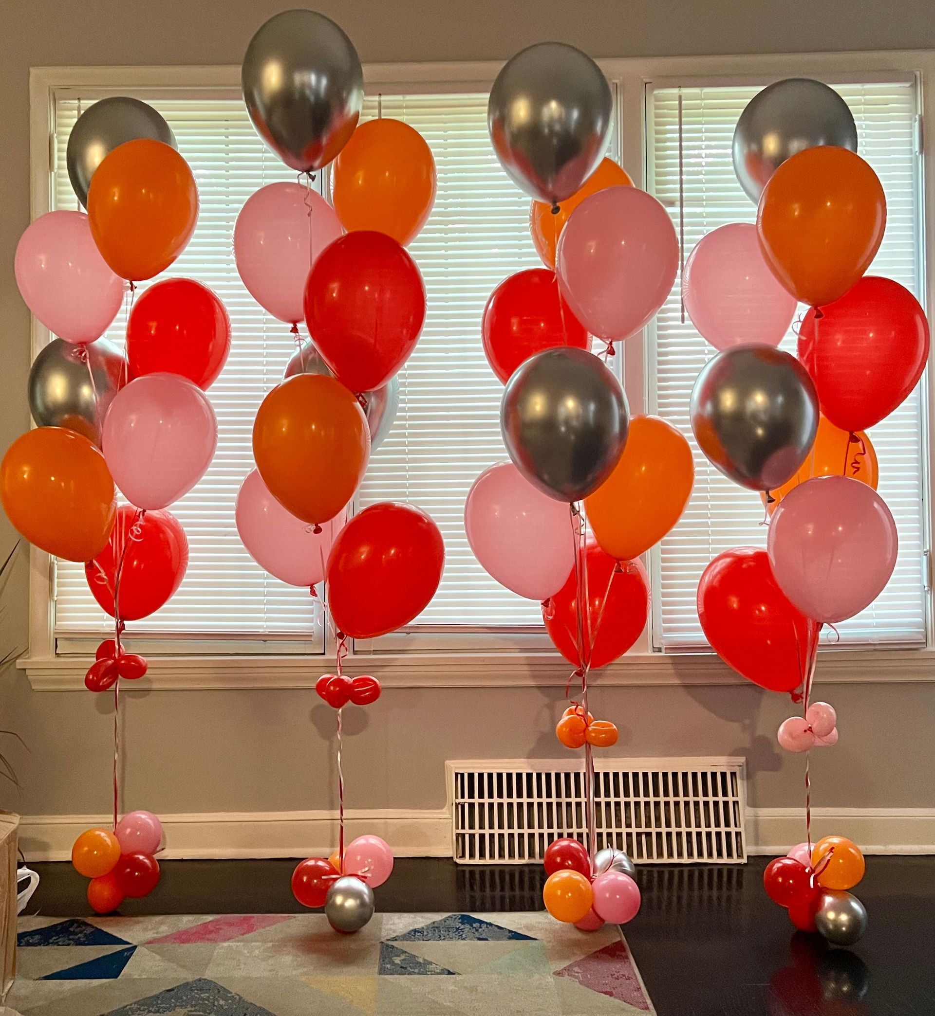 A bunch of balloons are lined up in front of a window
