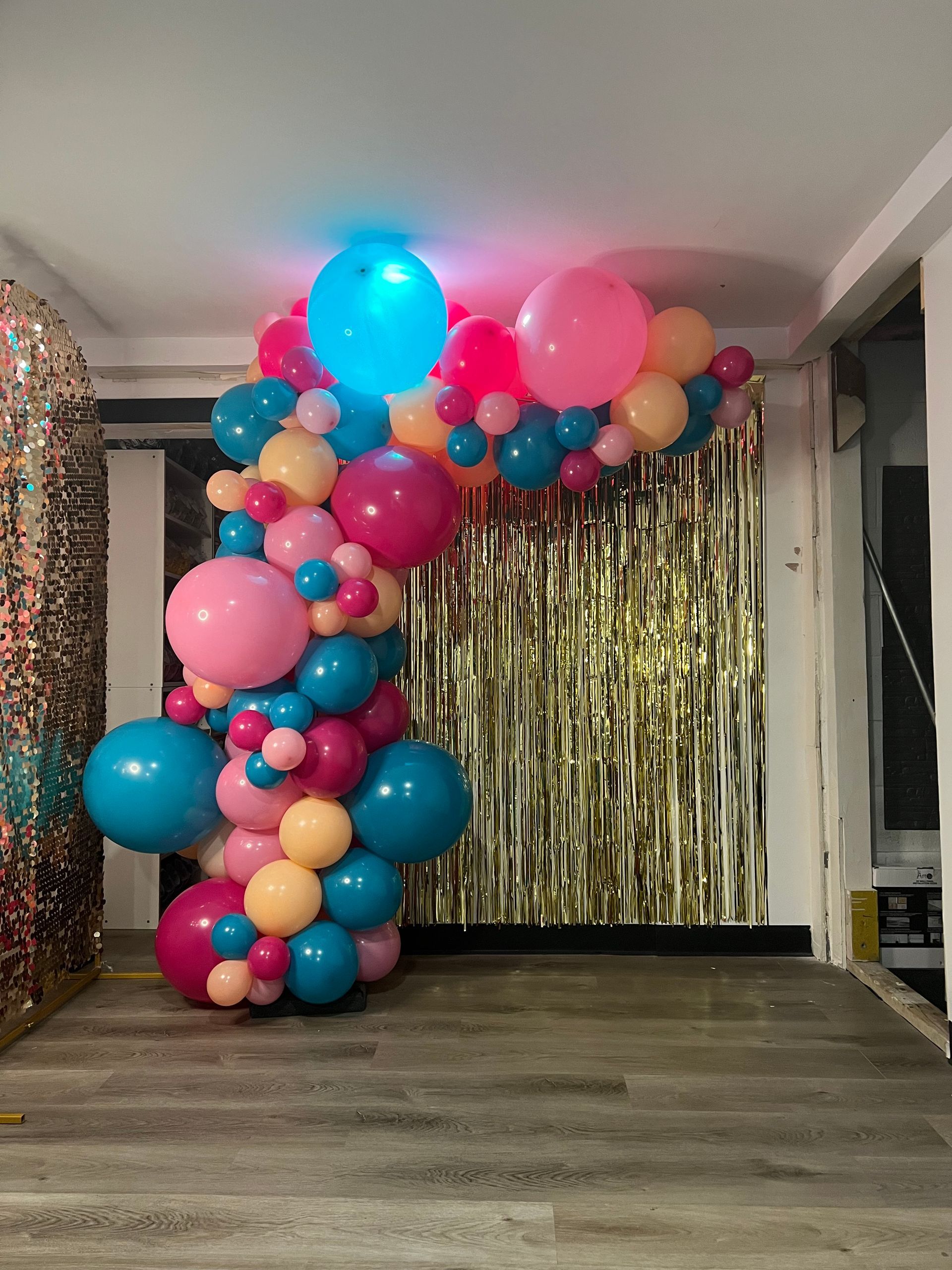 A room filled with balloons and a gold curtain.