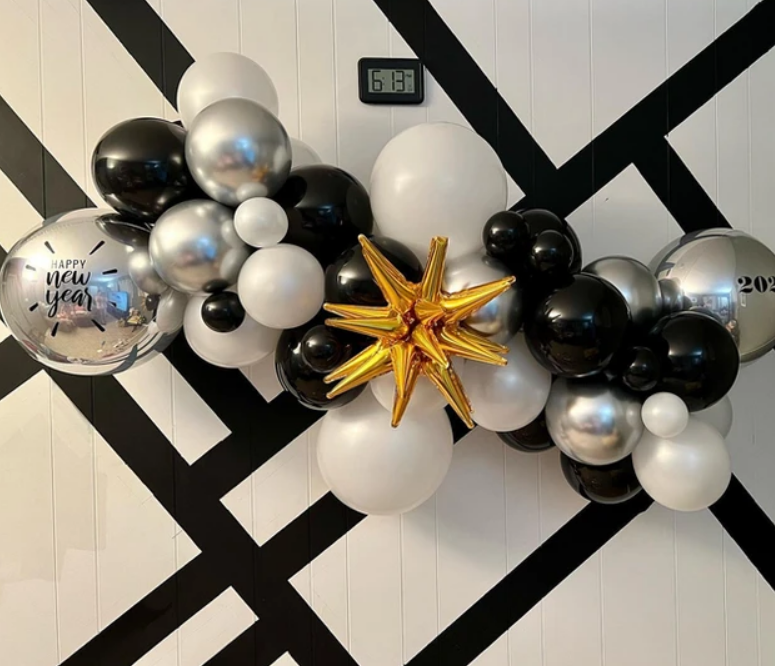 A bunch of black and white balloons on a wall