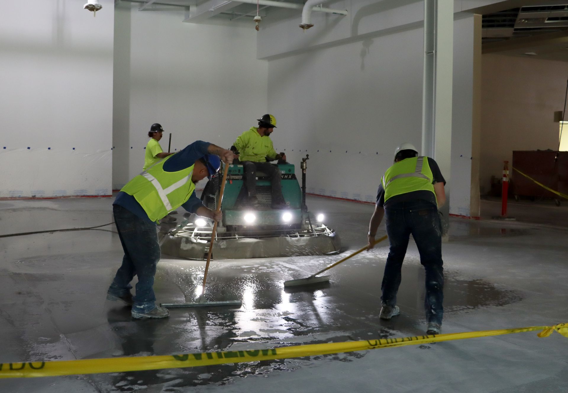 A group of construction workers are working on a concrete floor.
