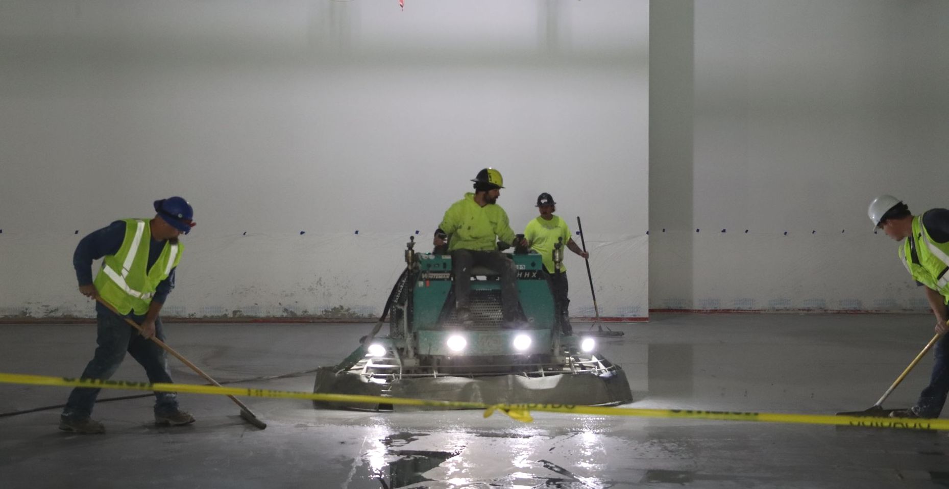 A group of construction workers are working on a concrete floor.