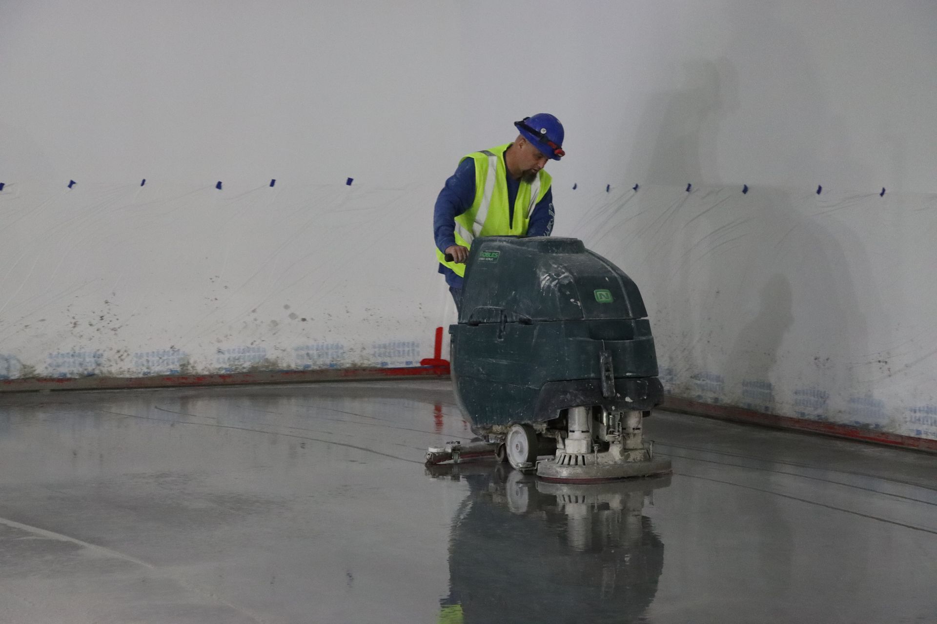 A man is using a machine to clean a concrete floor.