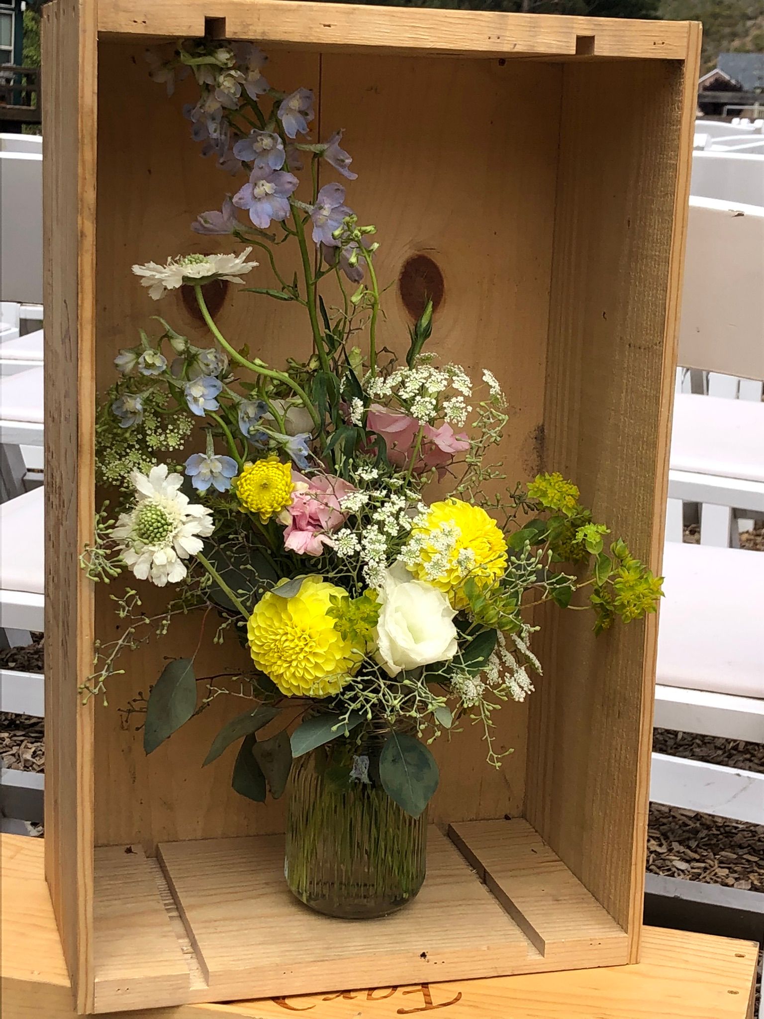 A vase filled with flowers is sitting in a wooden box.
