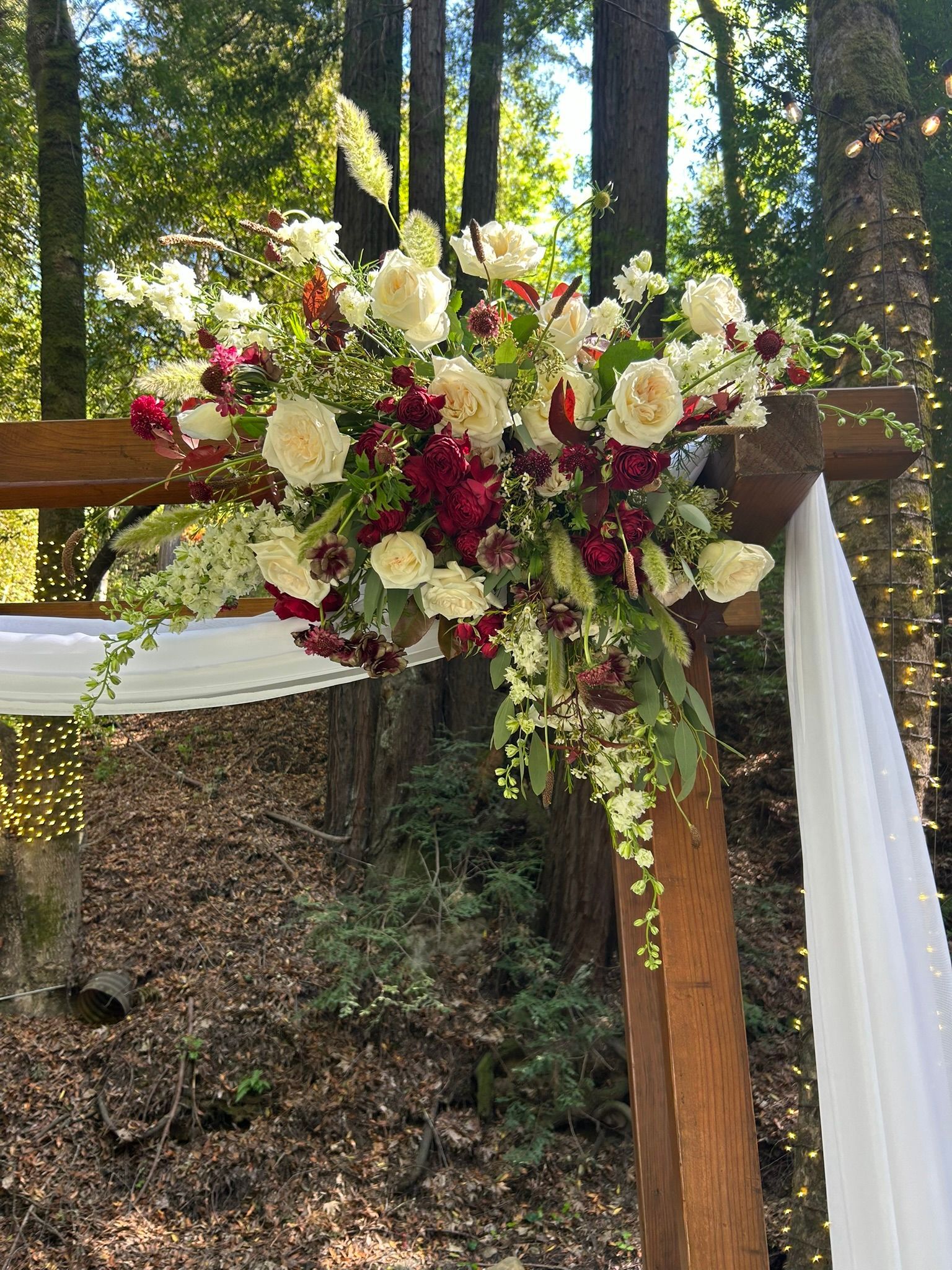 A wooden arch decorated with wildflowers and fabric