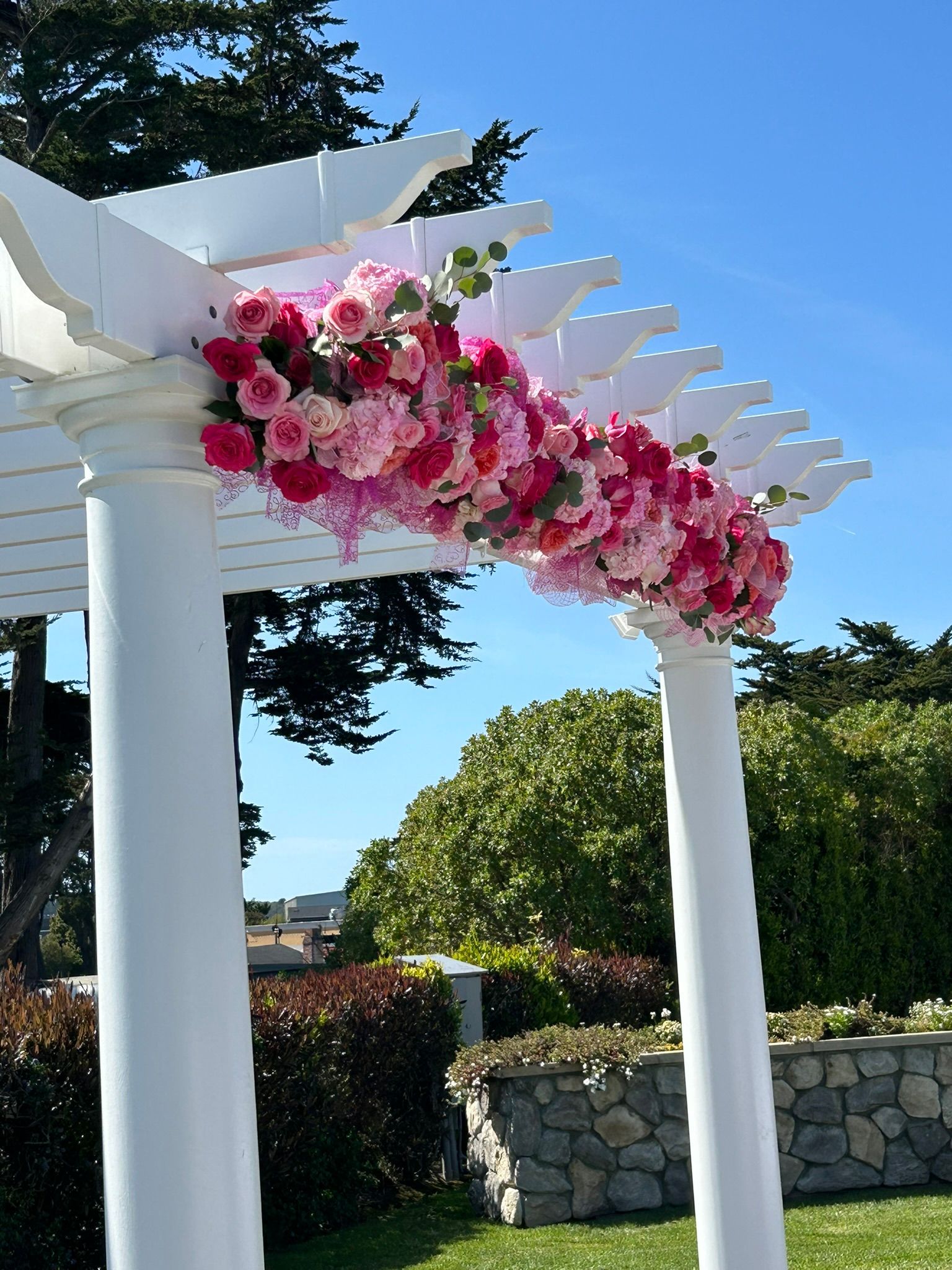 An elegant wedding pergola decorated with pink roses and ribbons.