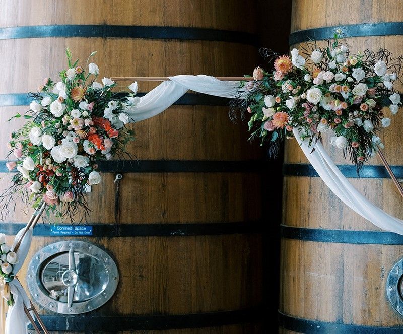 A modern wedding arch decorated with autumn flowers and fabric.