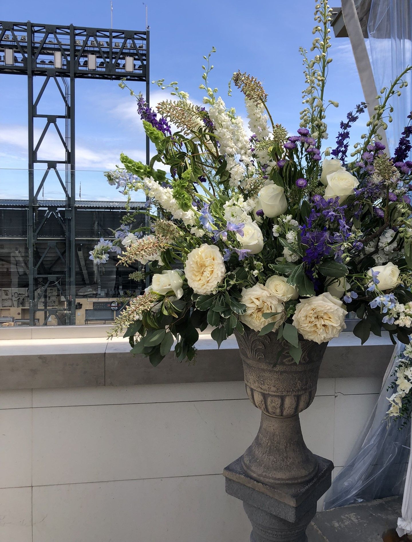 A large urn filled with white and blue flowers for a wedding ceremony.
