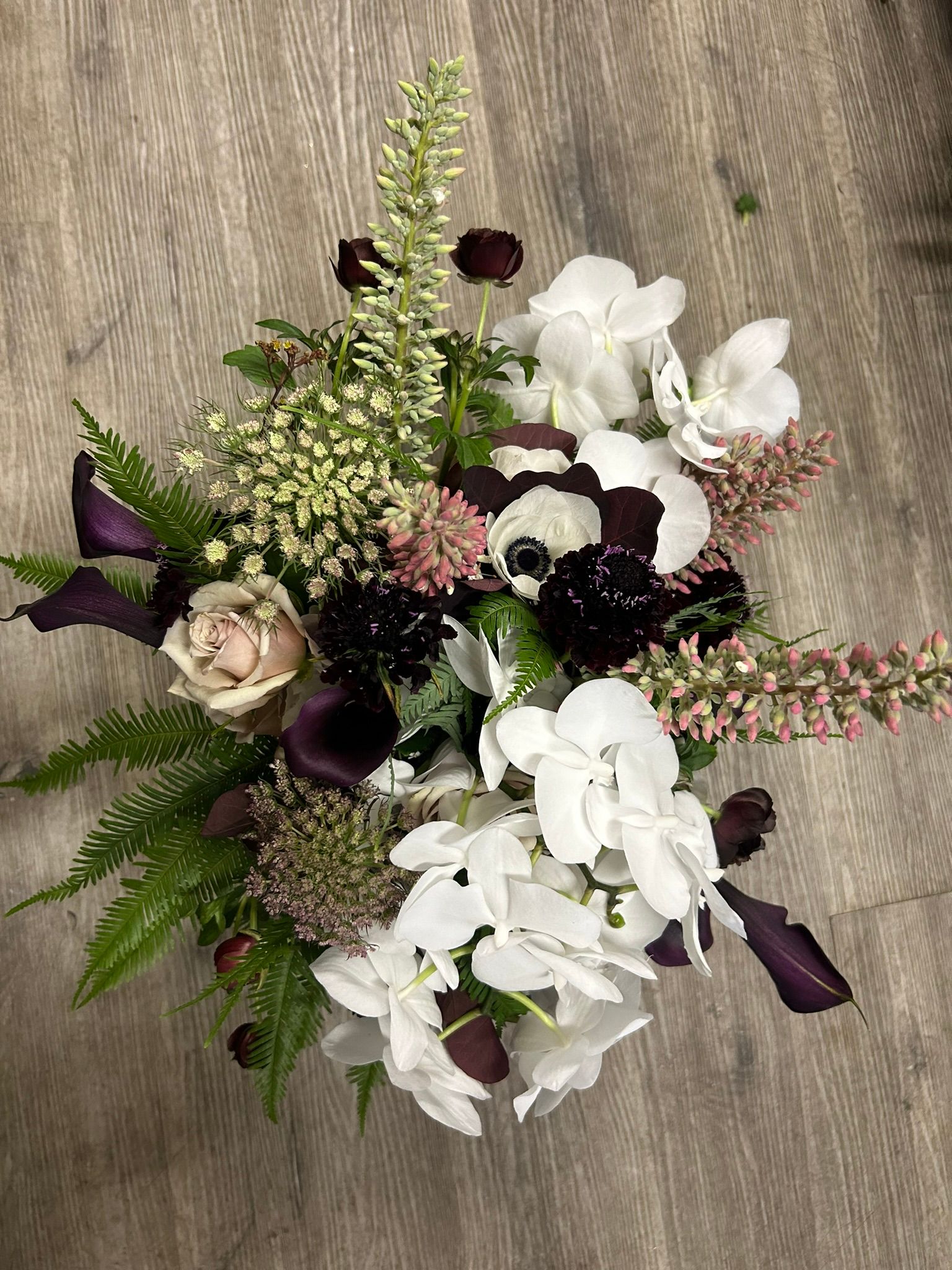A bouquet of flowers is sitting on a wooden table.