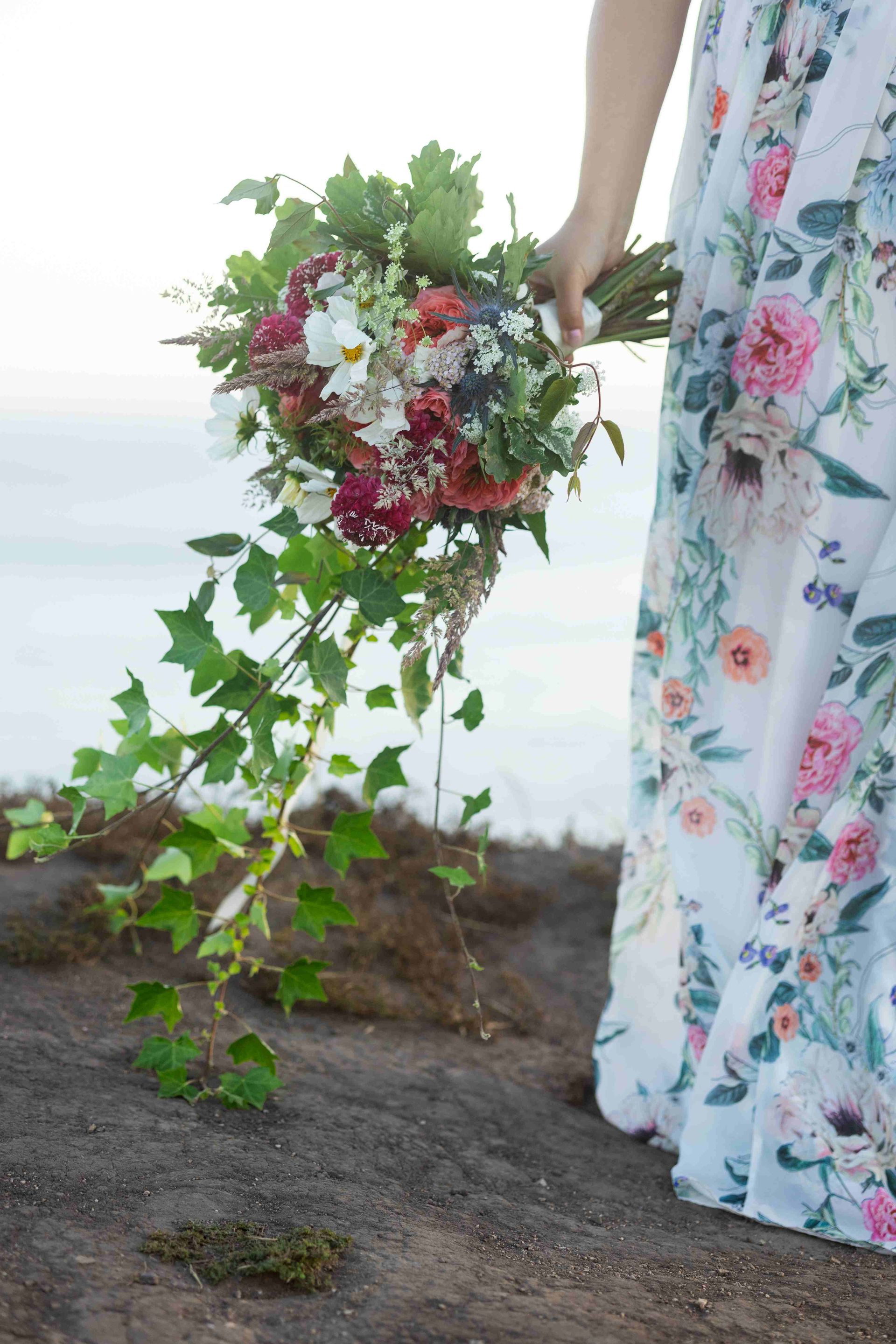A woman in a floral dress is holding a bouquet of flowers.