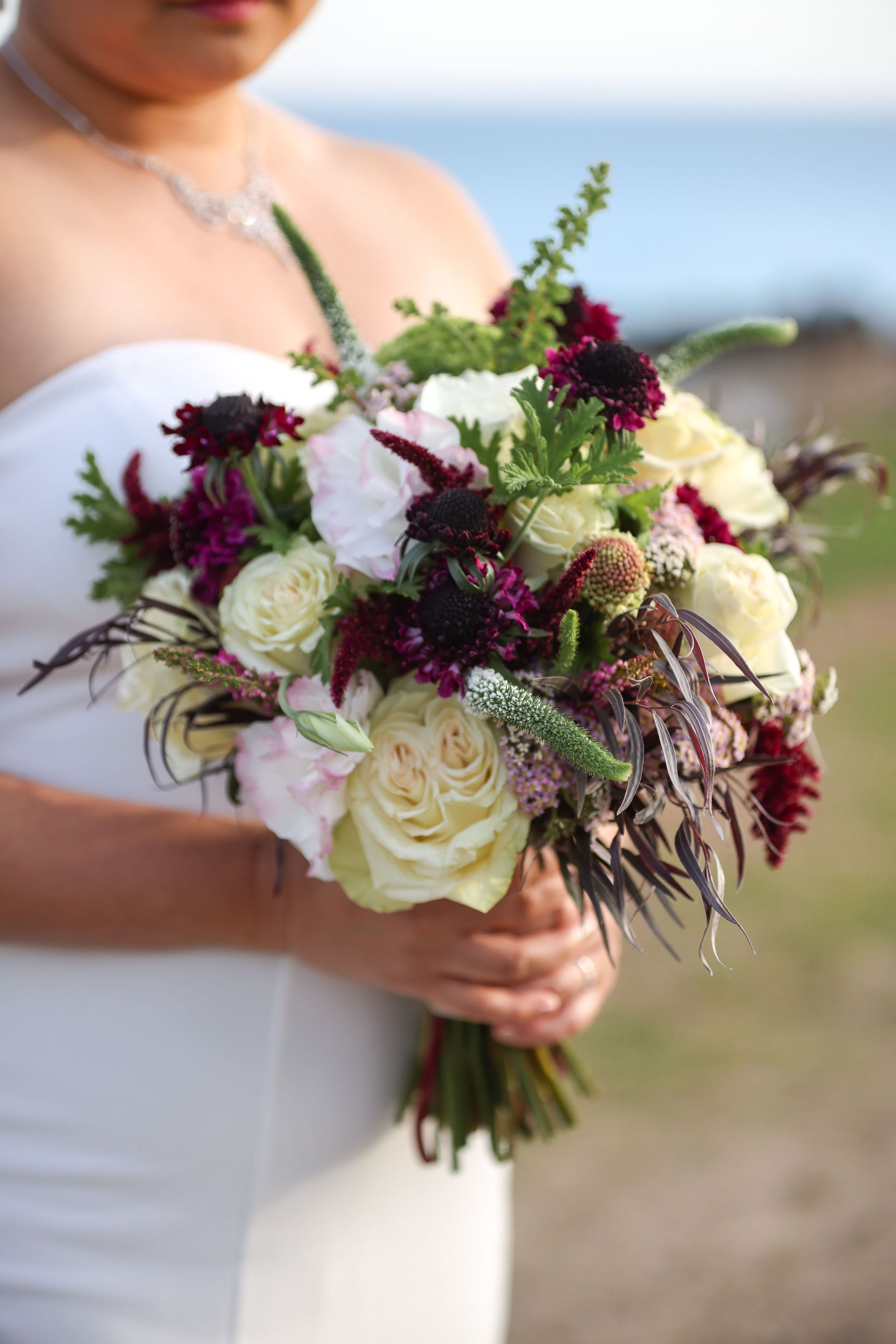A woman in a white dress is holding a bouquet of flowers.