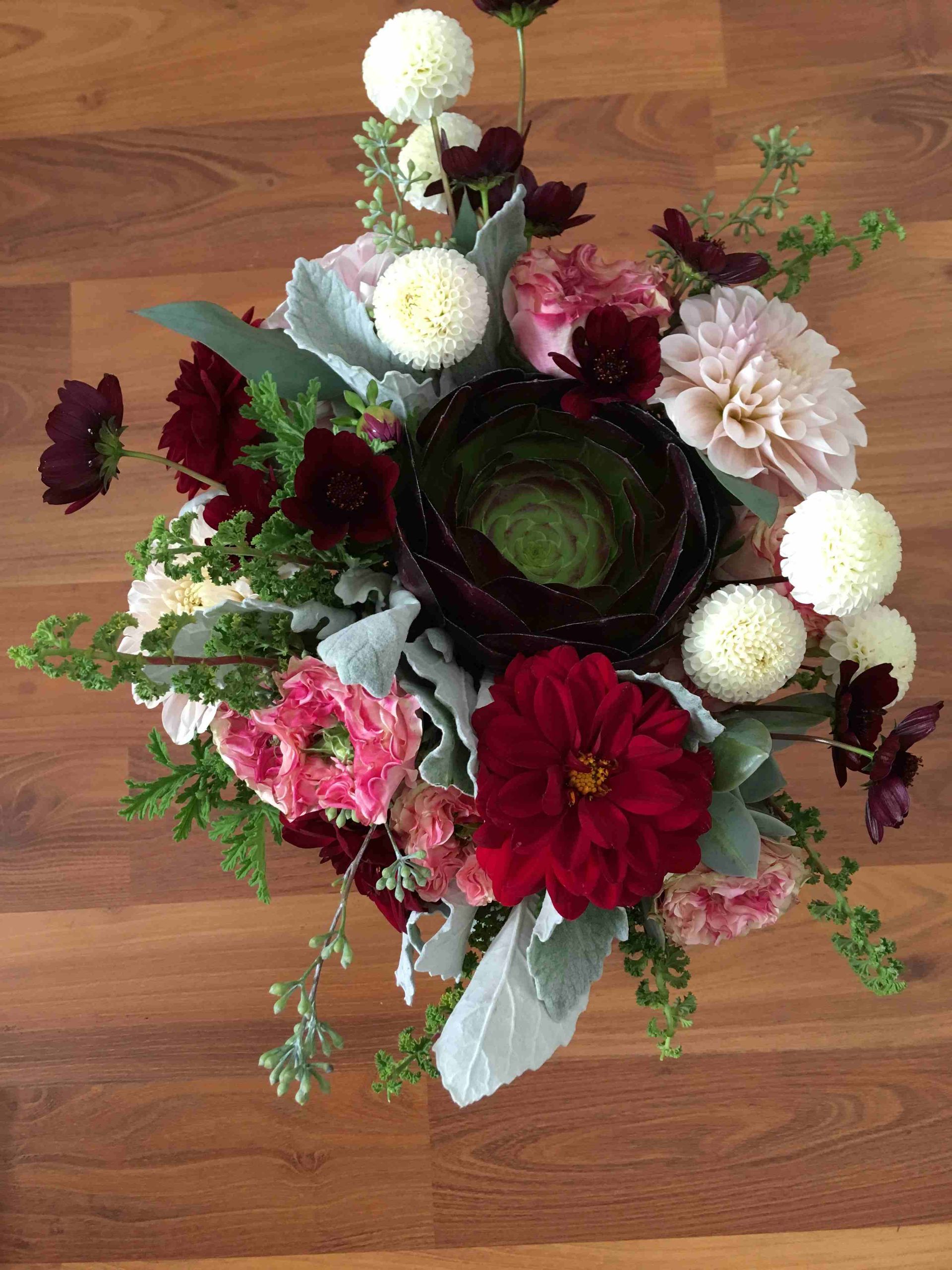 A bouquet of flowers is sitting on a wooden table.