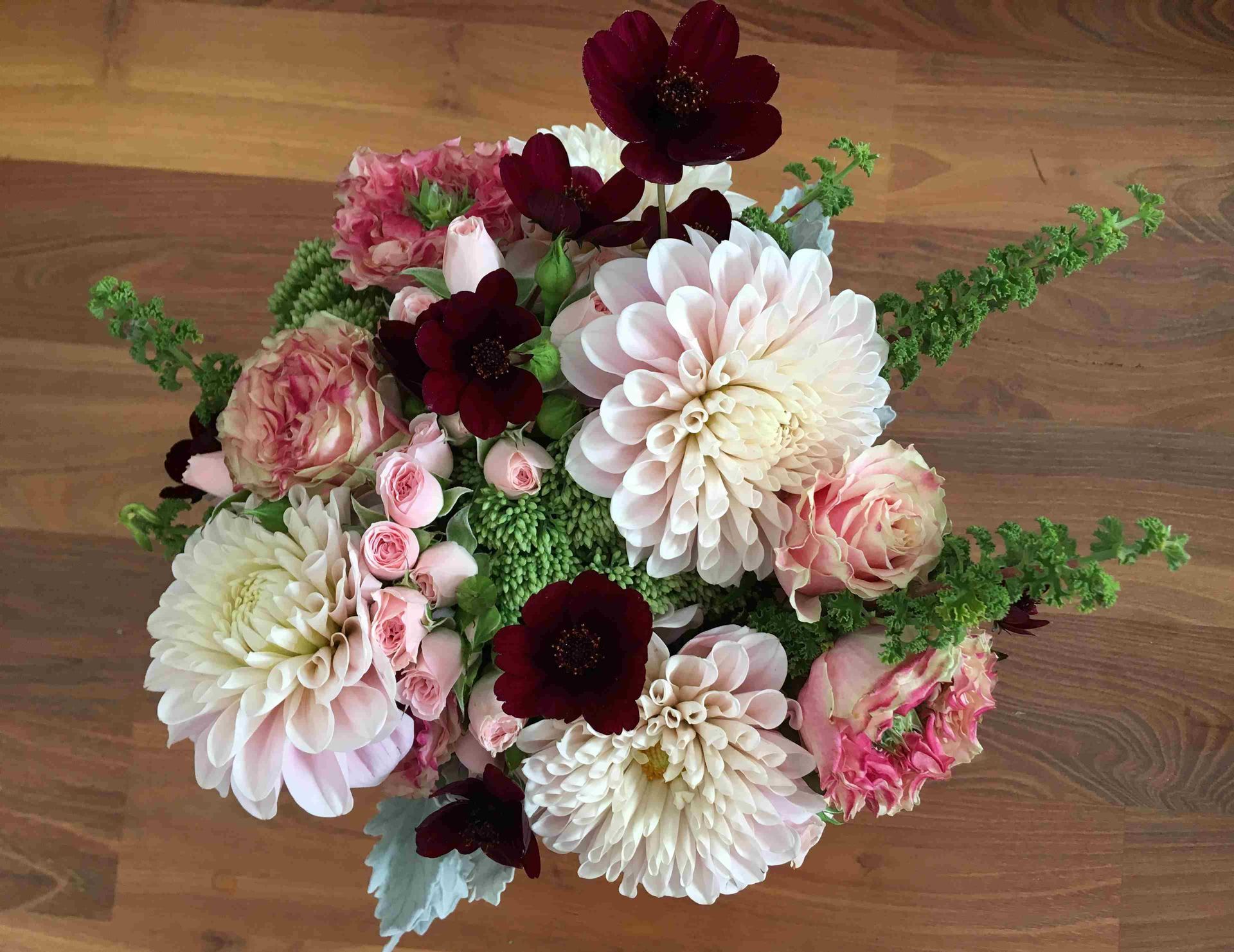 A bouquet of flowers is sitting on a wooden table.