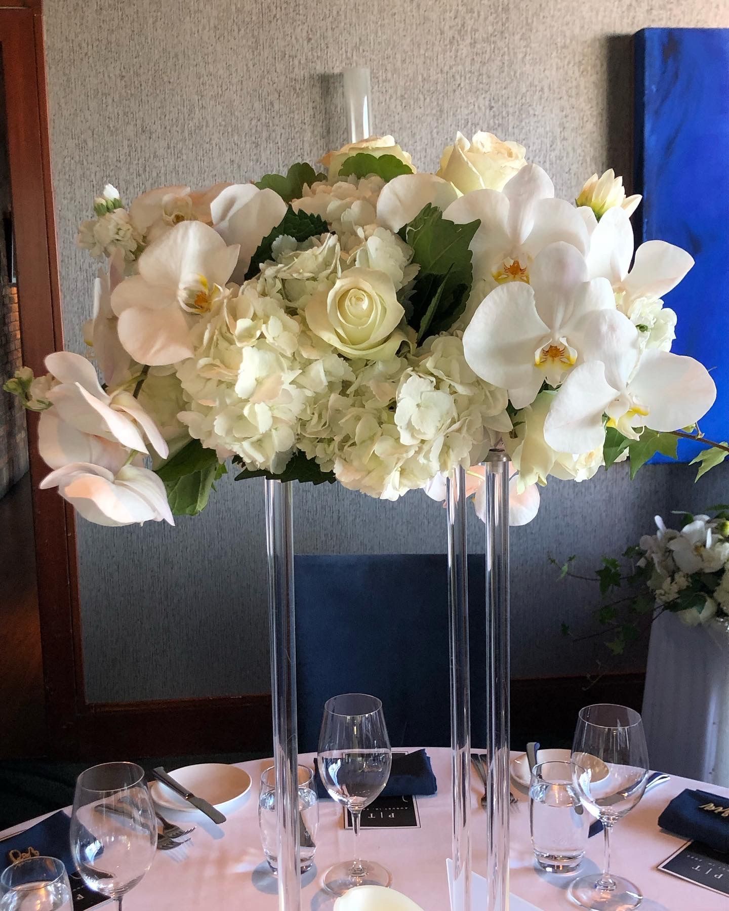 A tall vase filled with white flowers sits on a table.